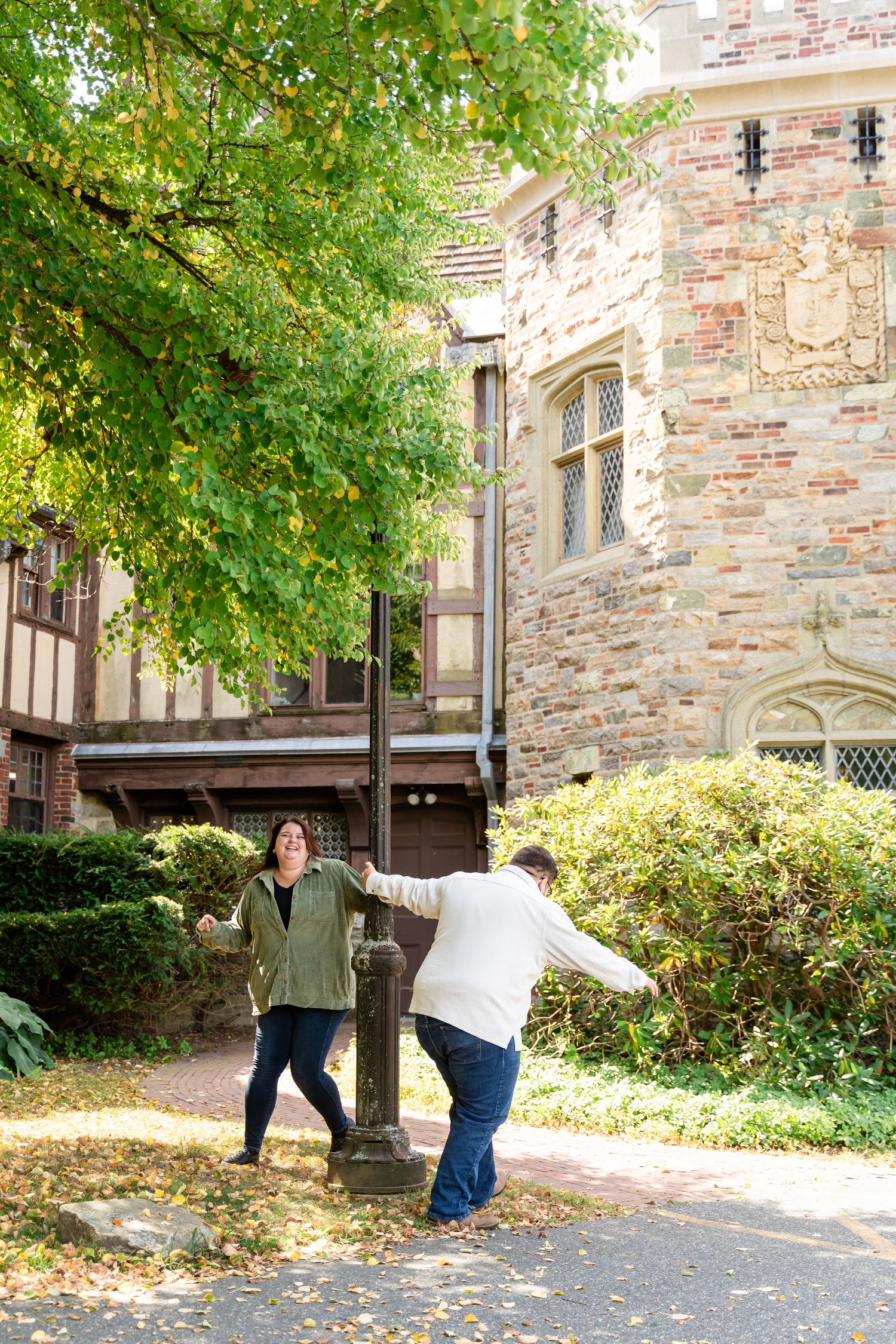 Couple playing and having fun outside historic stone building with autumn foliage.
