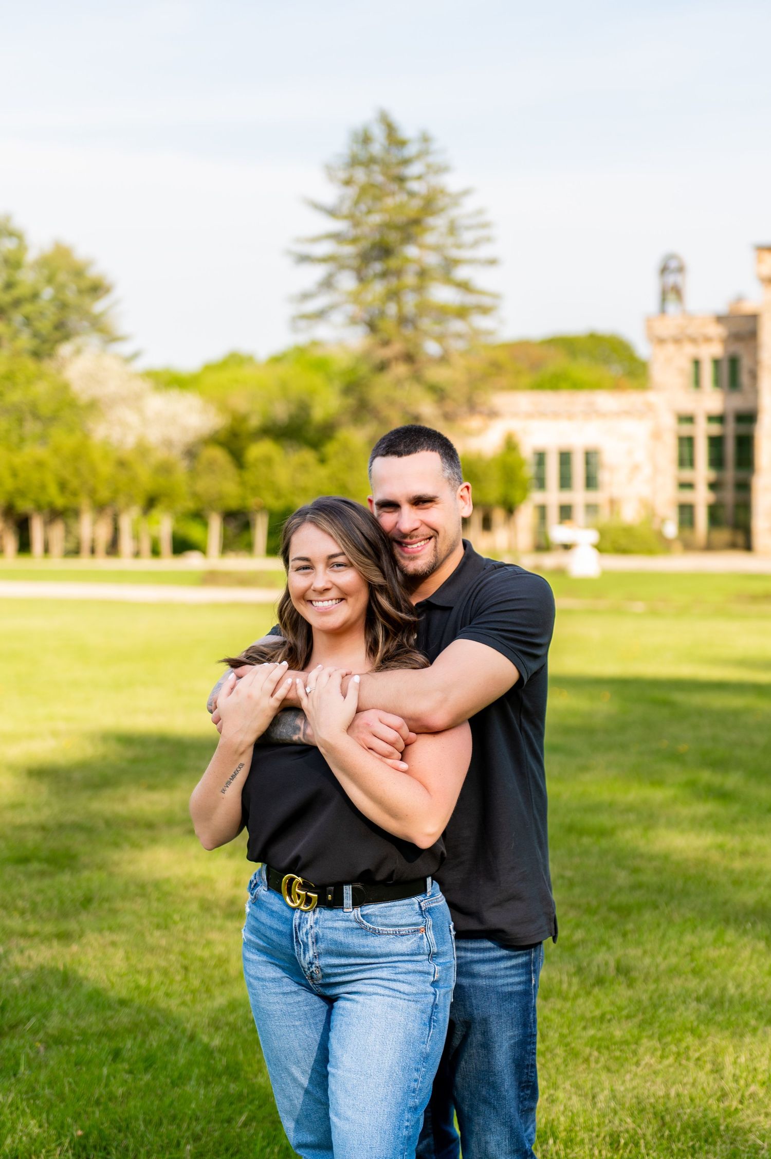 Romantic portrait of couple smiling and hugging outdoors on college campus grounds.