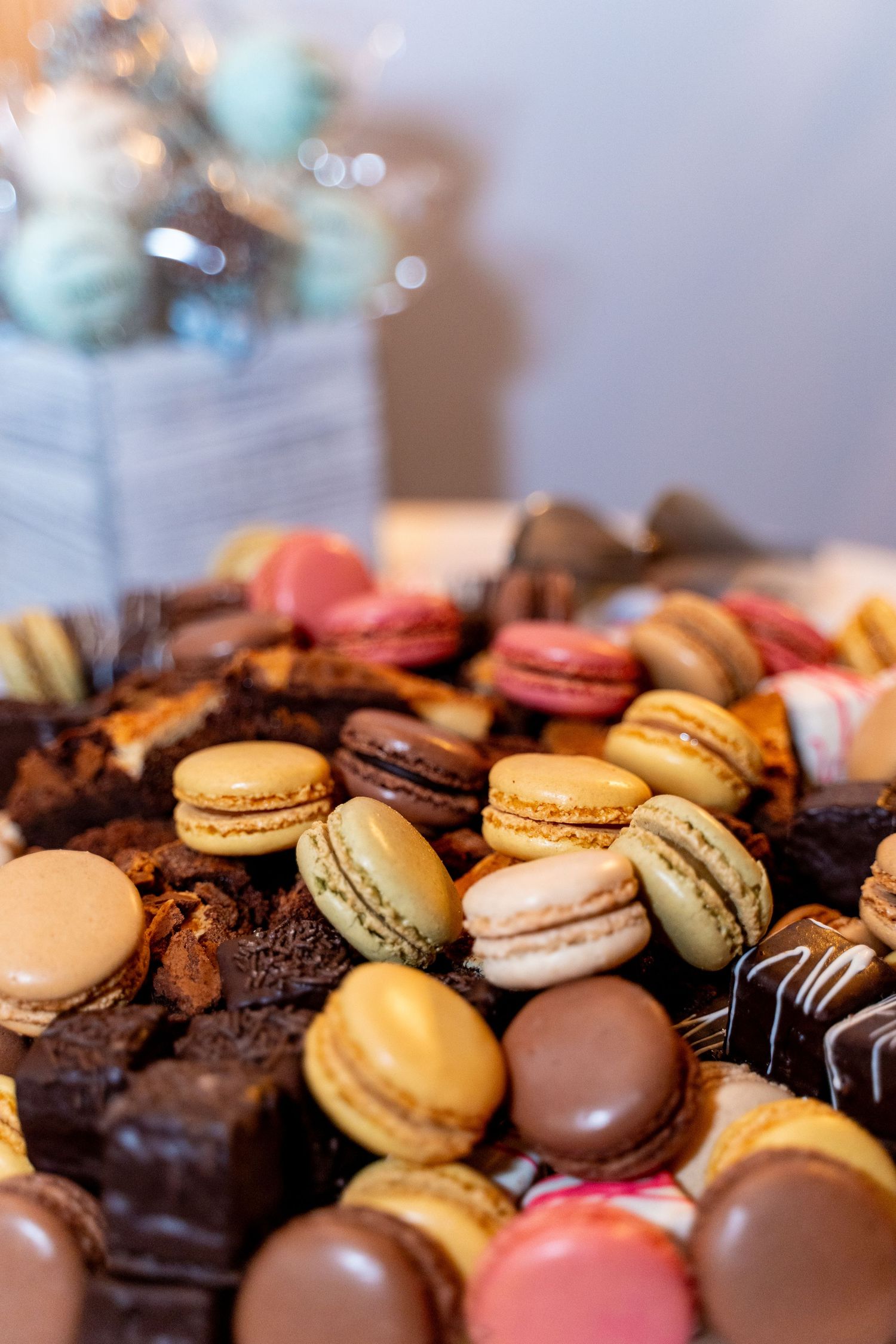 Colorful array of macarons and chocolates displayed at wedding dessert table.