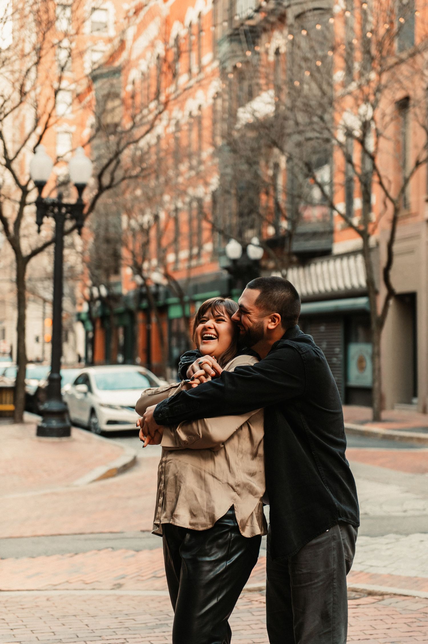 Joyful couple sharing romantic moment on brick paved street with historic buildings.