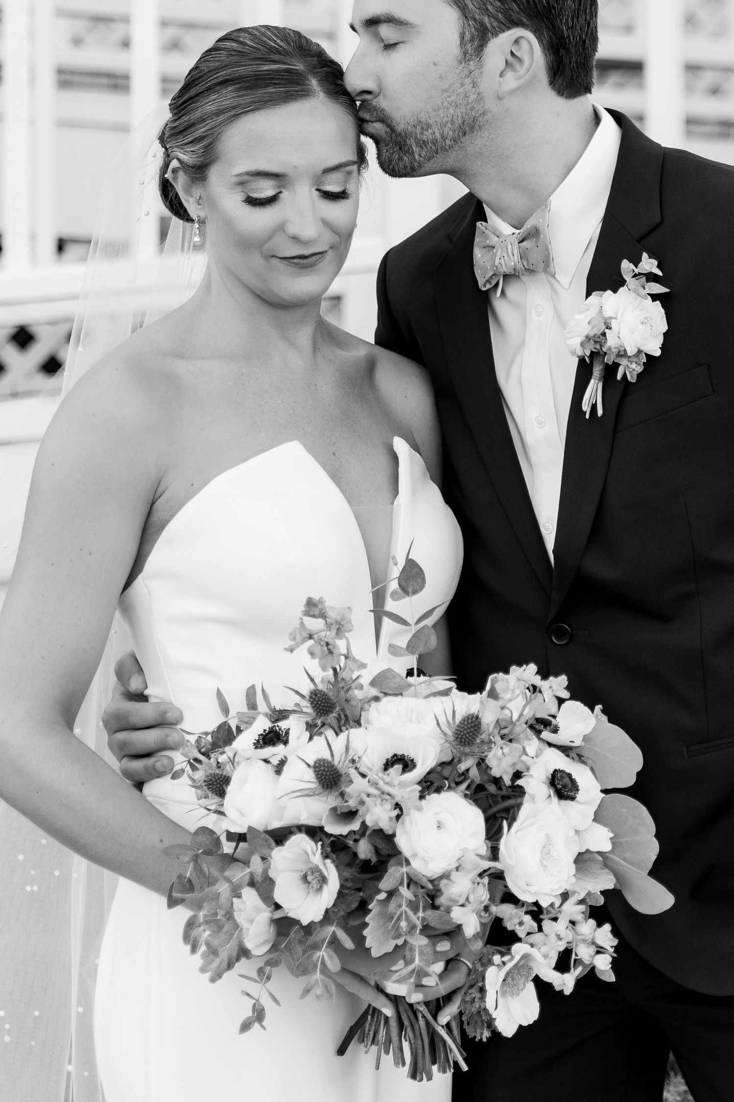 Black and white close-up wedding portrait with delicate white floral bouquet.
