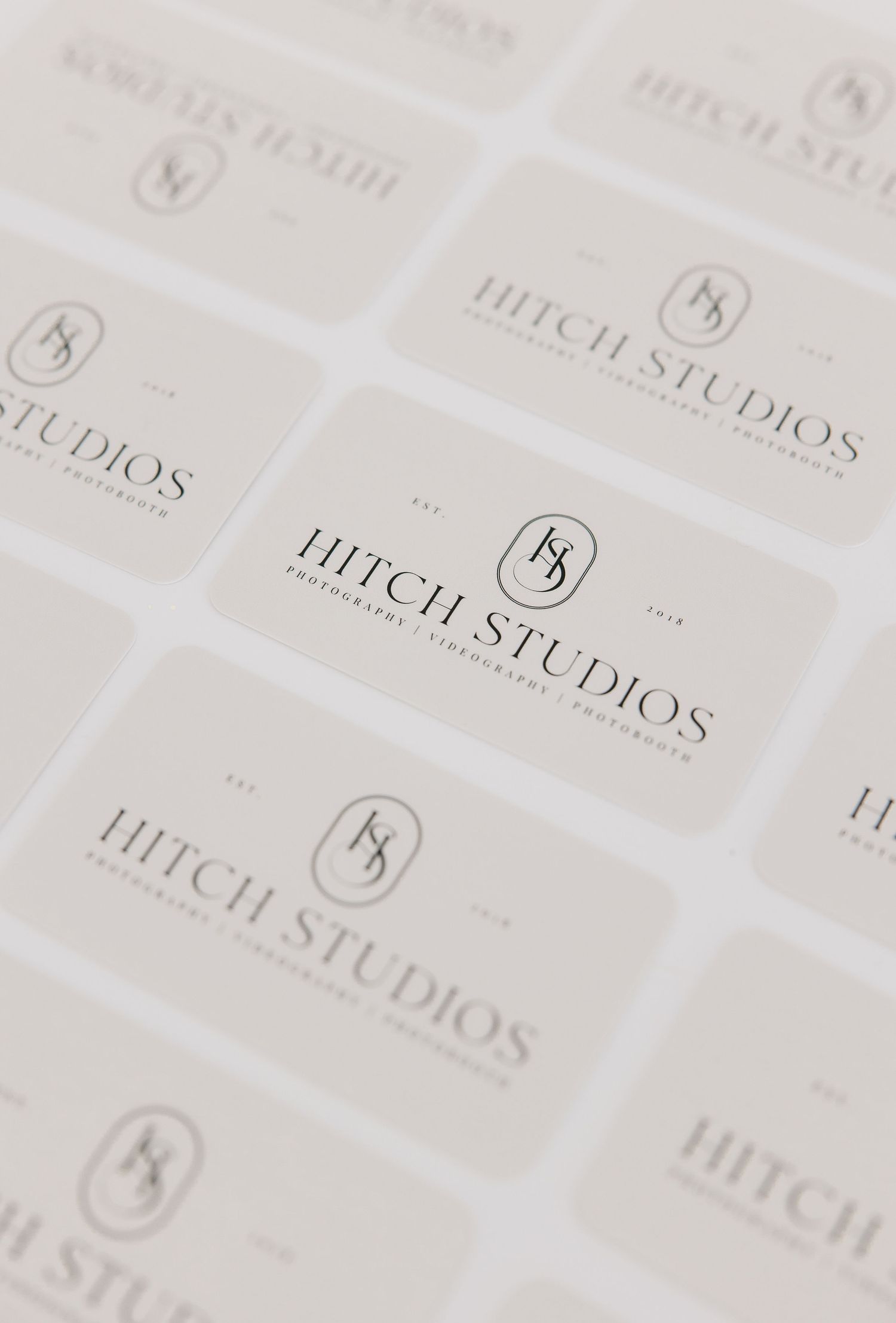 Repeating pattern of Hitch Studios logo text printed in gray on white background creates a subtle diagonal design.
