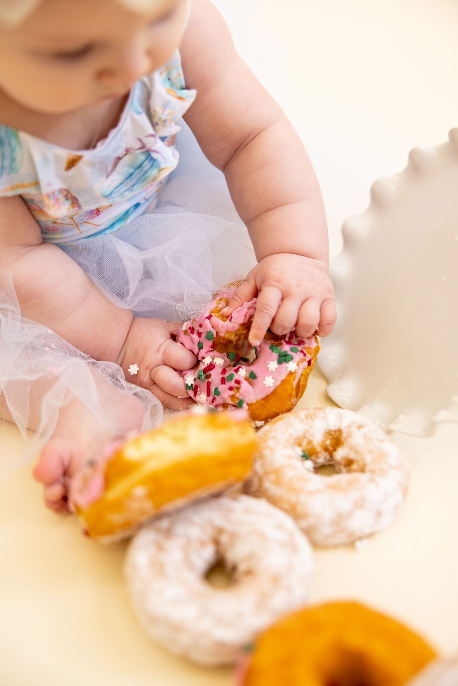 Close-up of small hands reaching for colorful frosted donuts during party photoshoot.