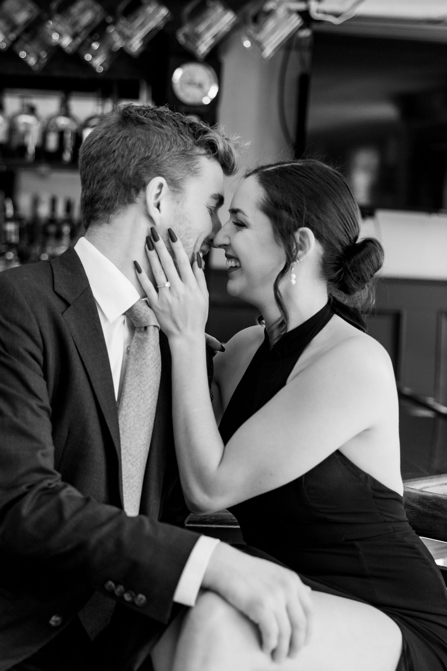 Intimate black and white portrait of couple sharing romantic moment at bar.