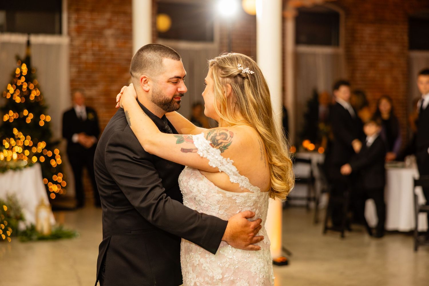 Newlyweds share their first dance in front of a decorated Christmas tree at their reception.