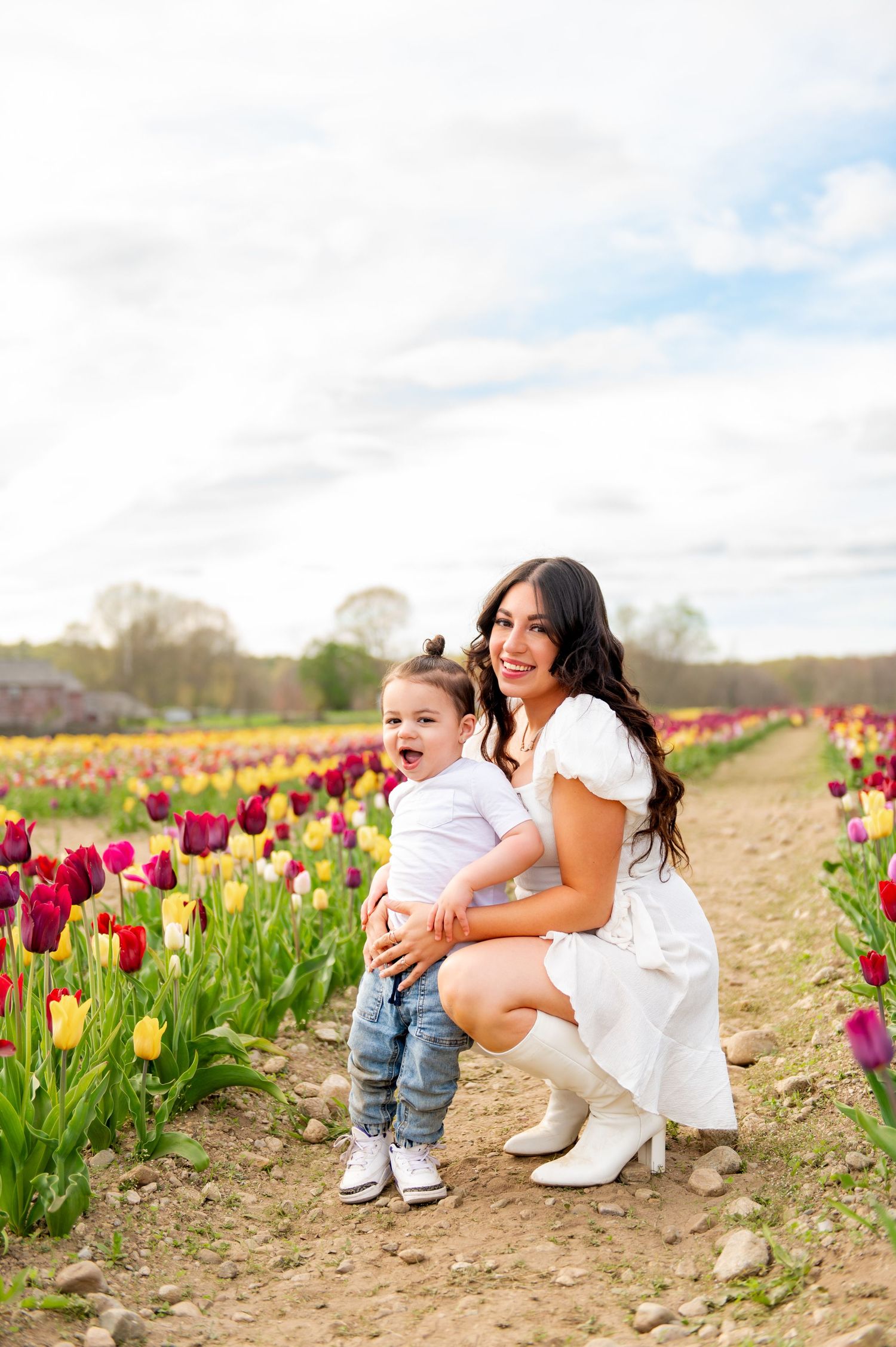 Colorful tulip field with vibrant pink and red flowers under cloudy spring sky.