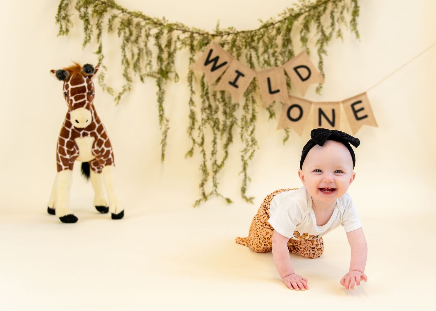 Wild One themed birthday setup with jungle decorations and giraffe plush toy.