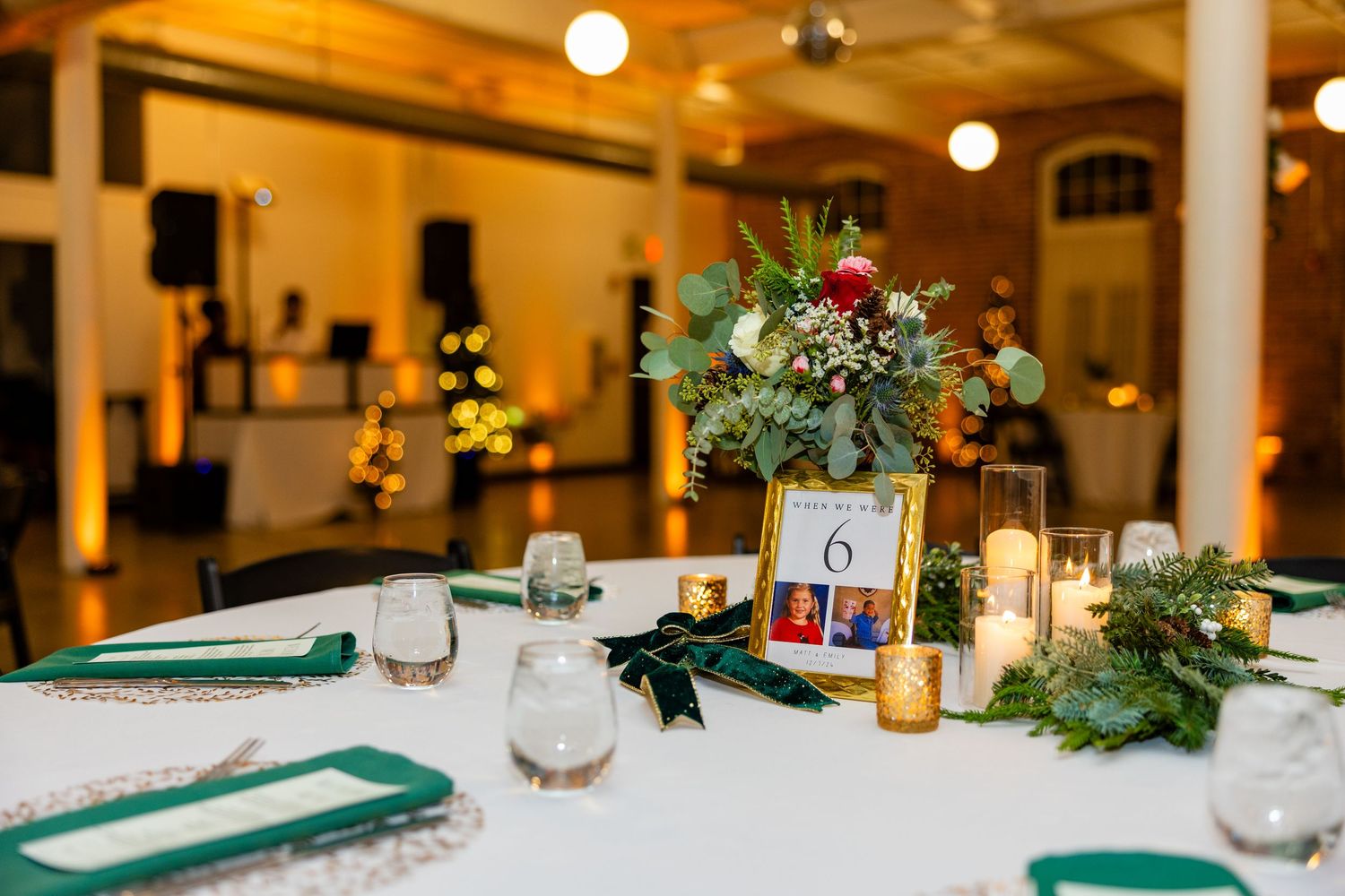 Elegant wedding table setting with floral centerpiece, table number, and green napkins.