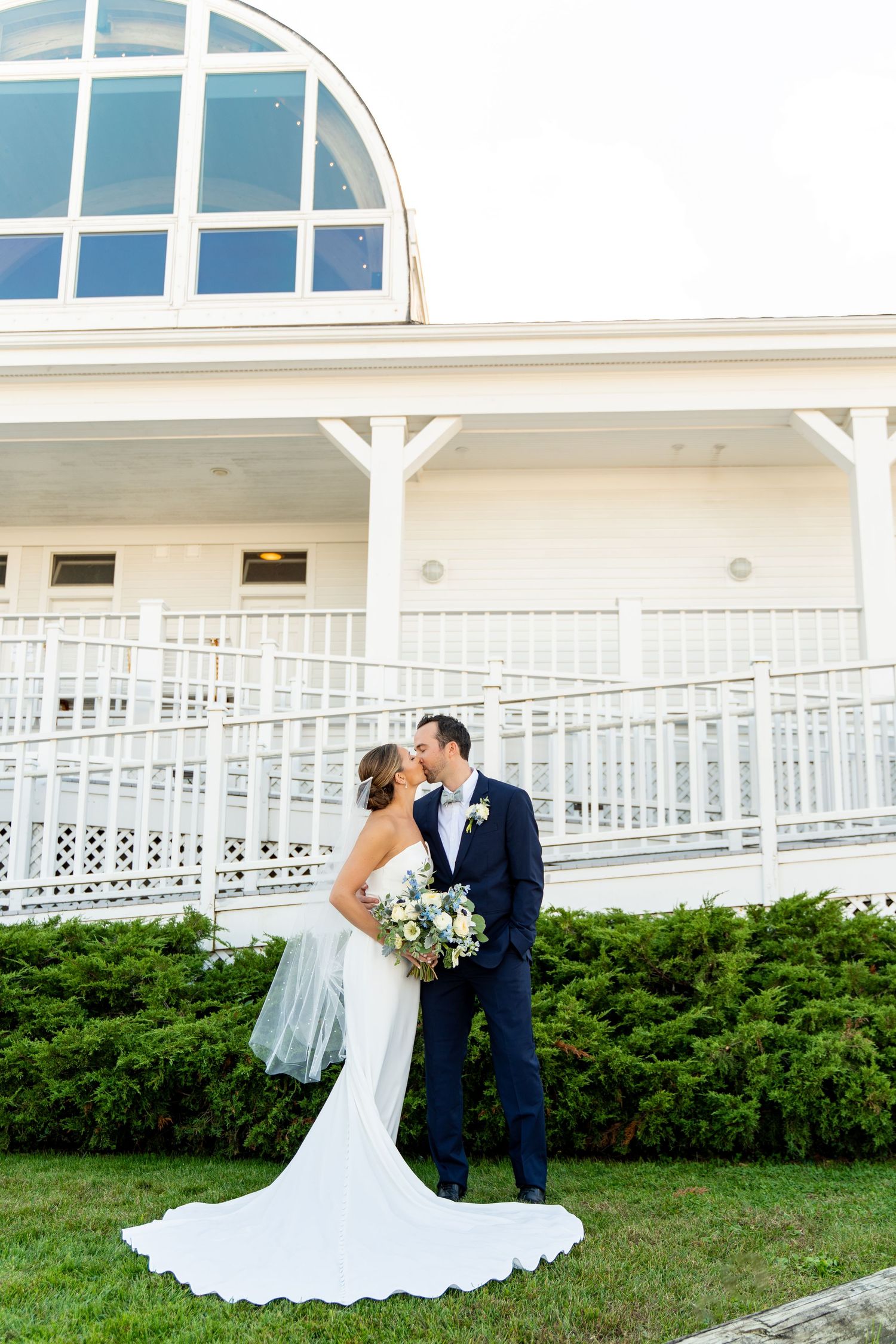 Romantic wedding portrait featuring flowing white dress against architectural backdrop.