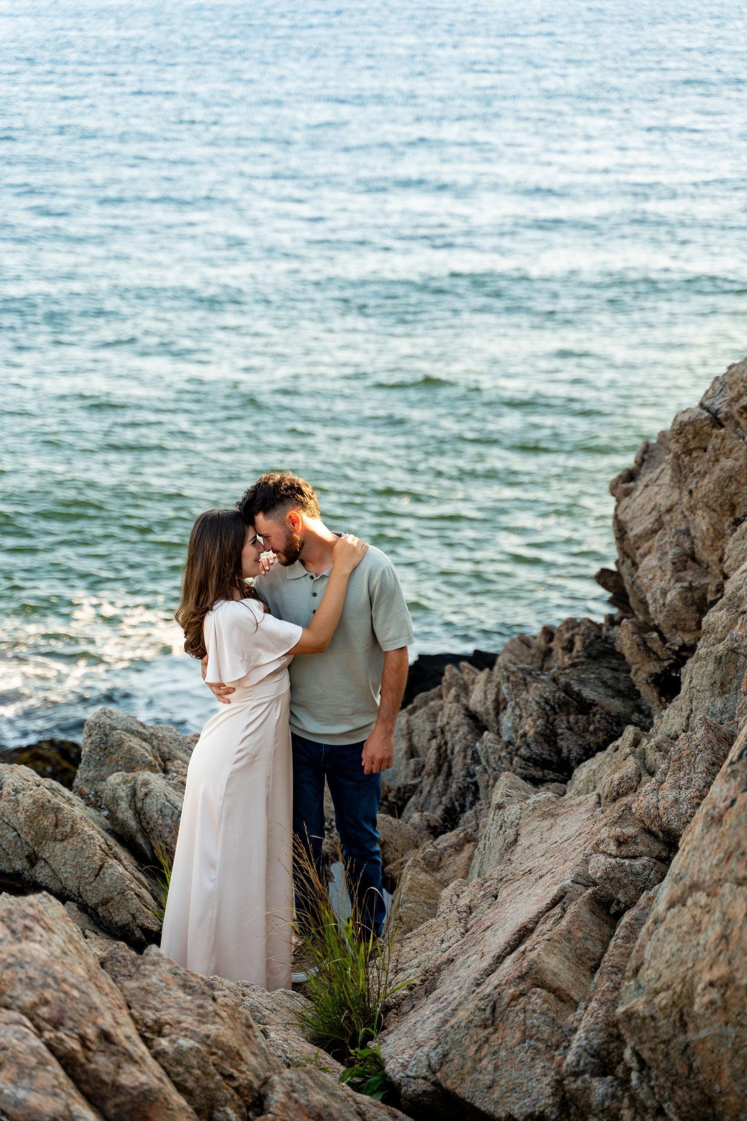 Romantic seaside portrait on rocky coastal cliffs at sunset.