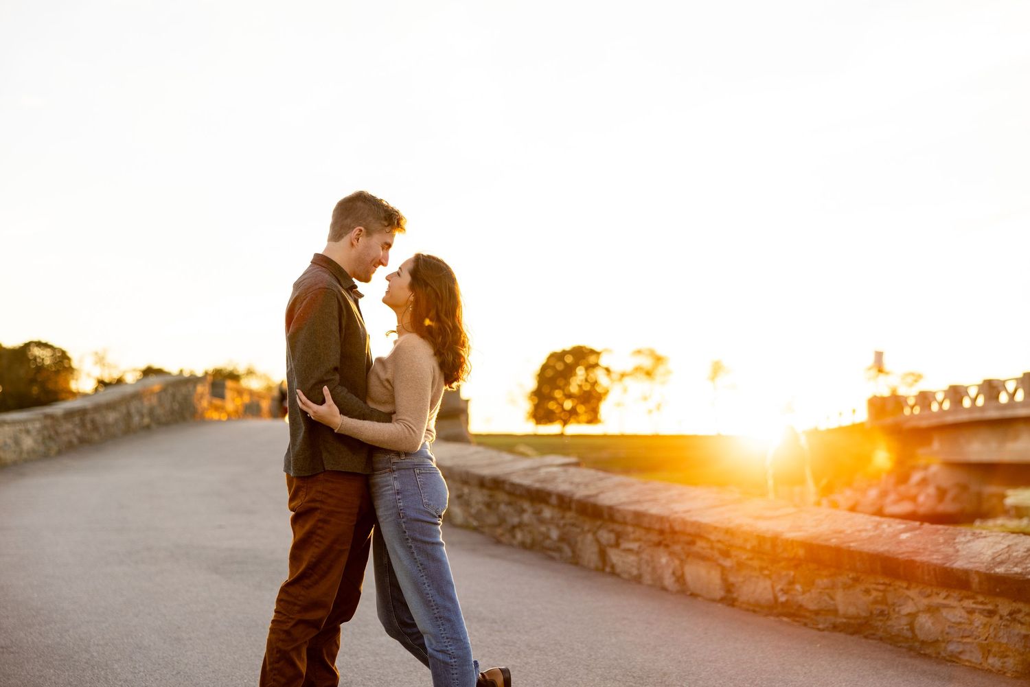 A romantic sunset moment between a couple on a stone bridge.