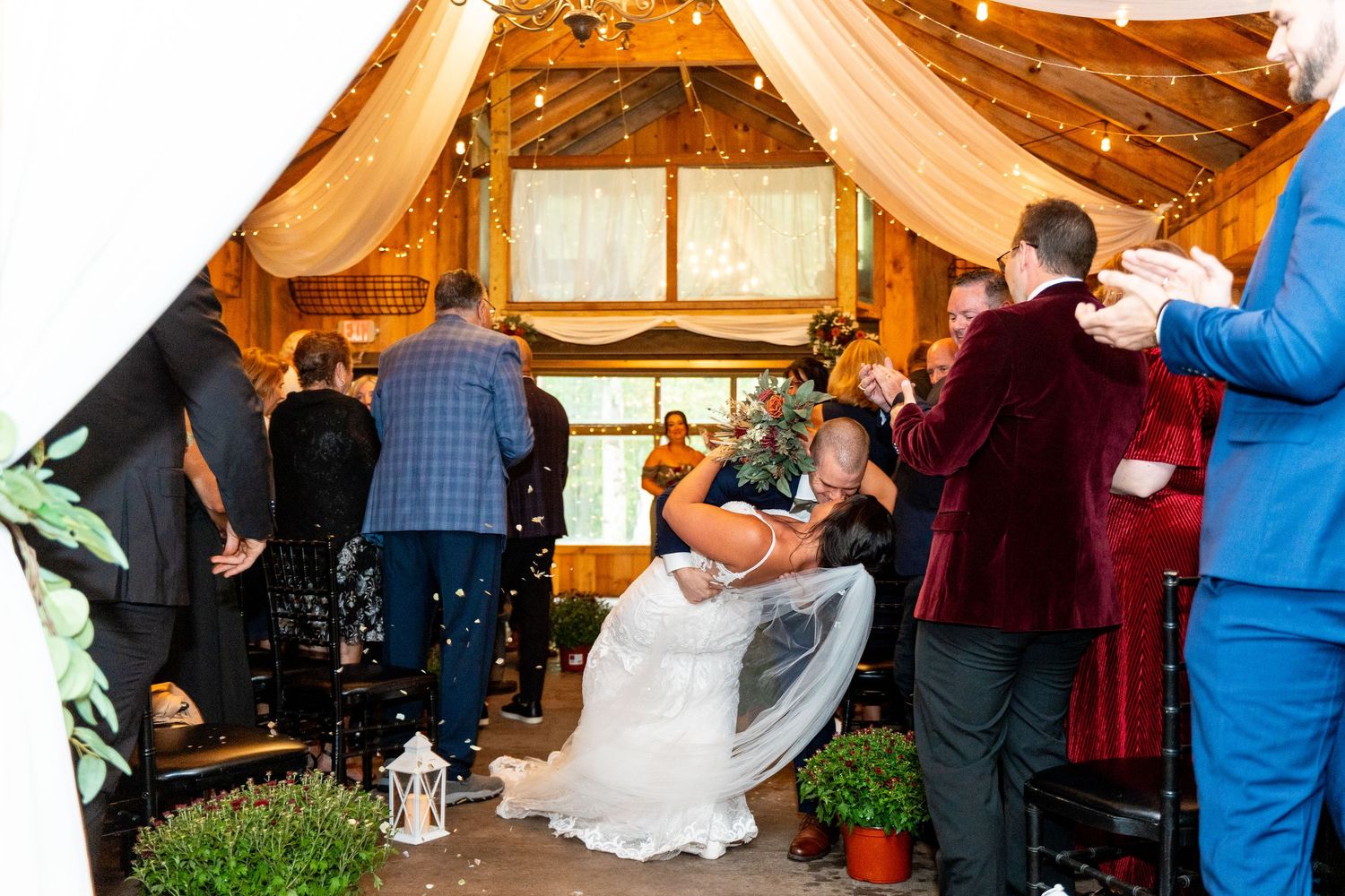Celebration inside rustic barn venue with guests throwing confetti at wedding couple.