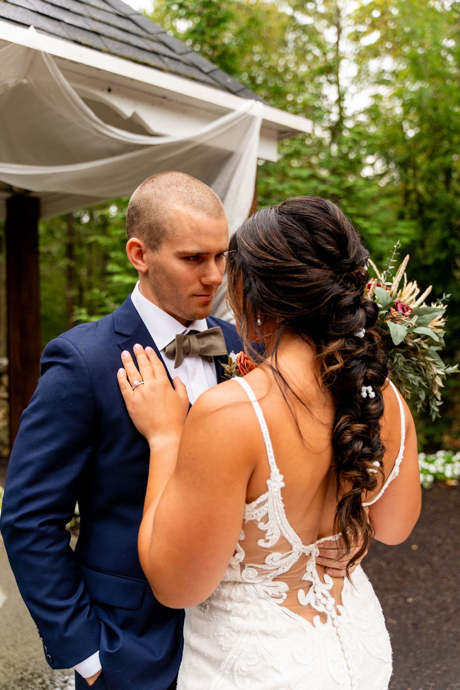 Beautiful wedding moment under white draped gazebo with floral decorations.