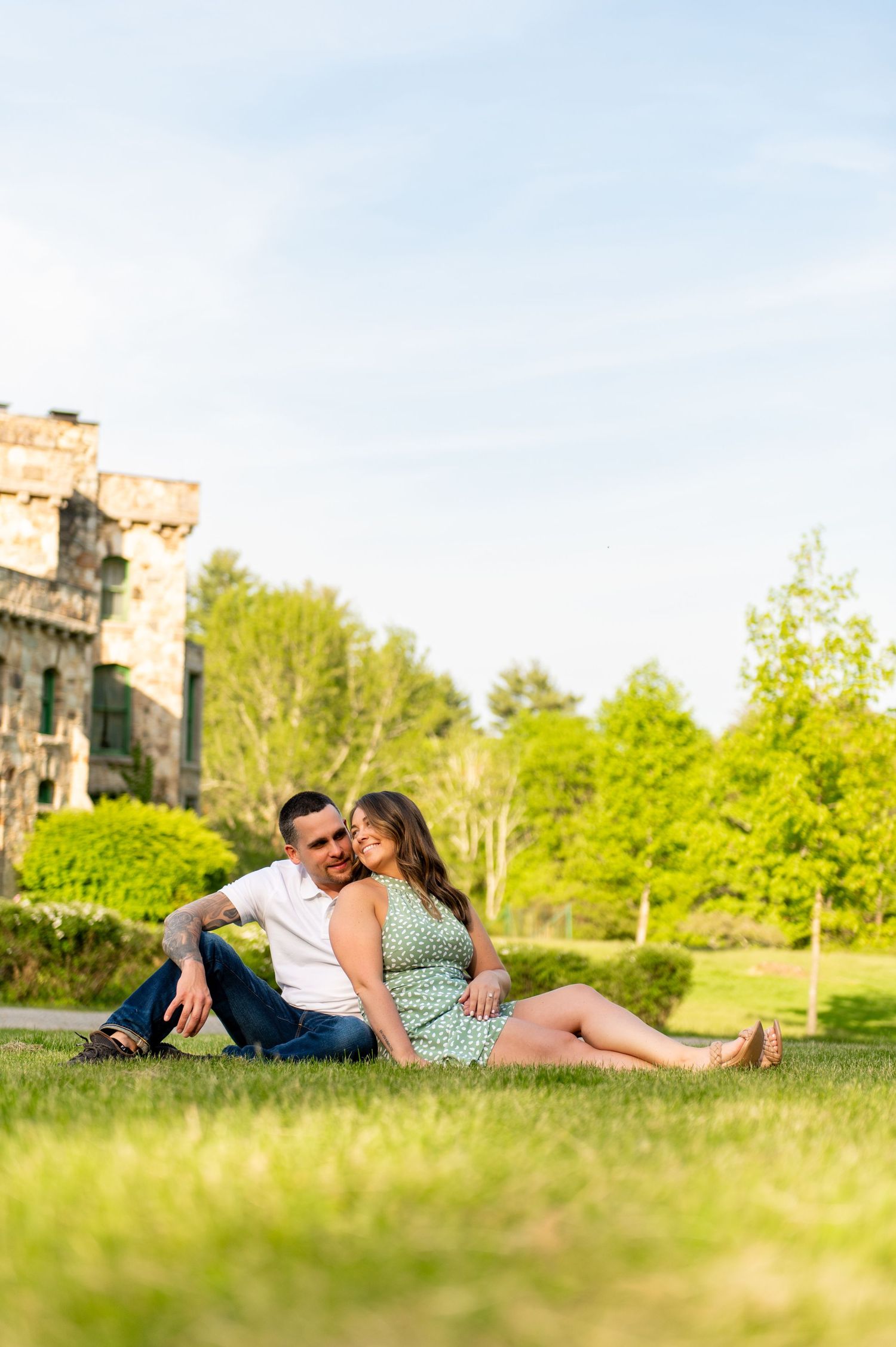 Couple relaxing together on grass near historic building on sunny spring day.