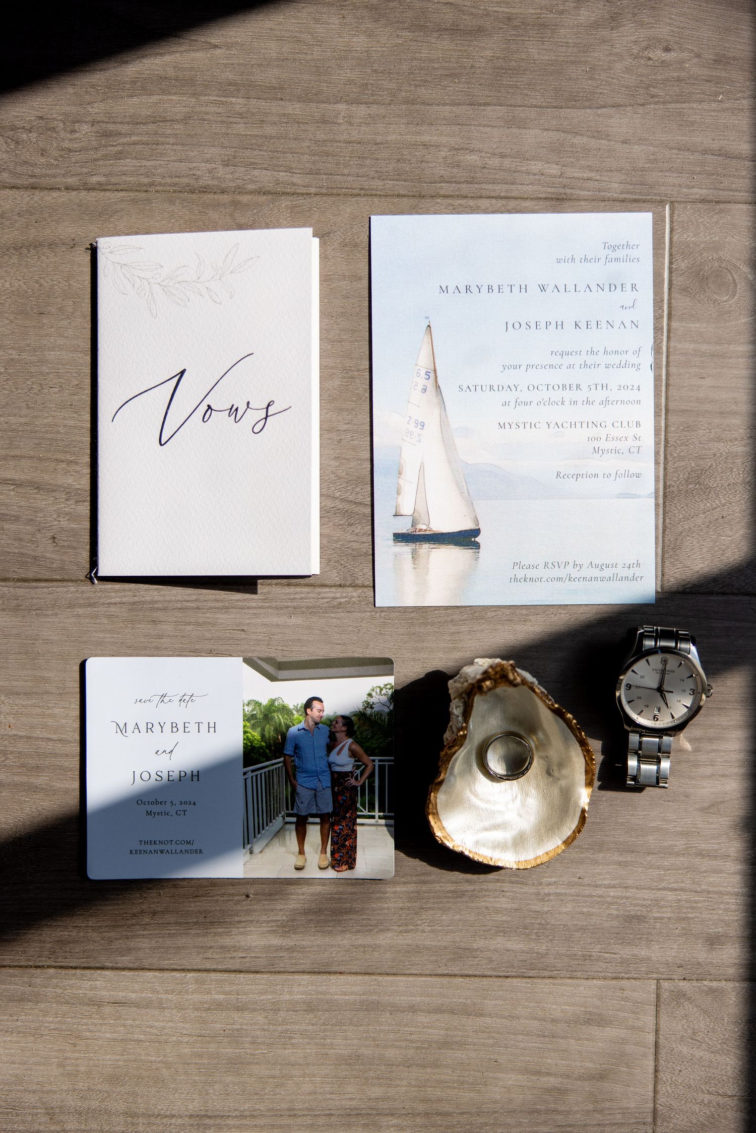 Wedding invitation suite with vows book, nautical design, and oyster shell on wooden surface.