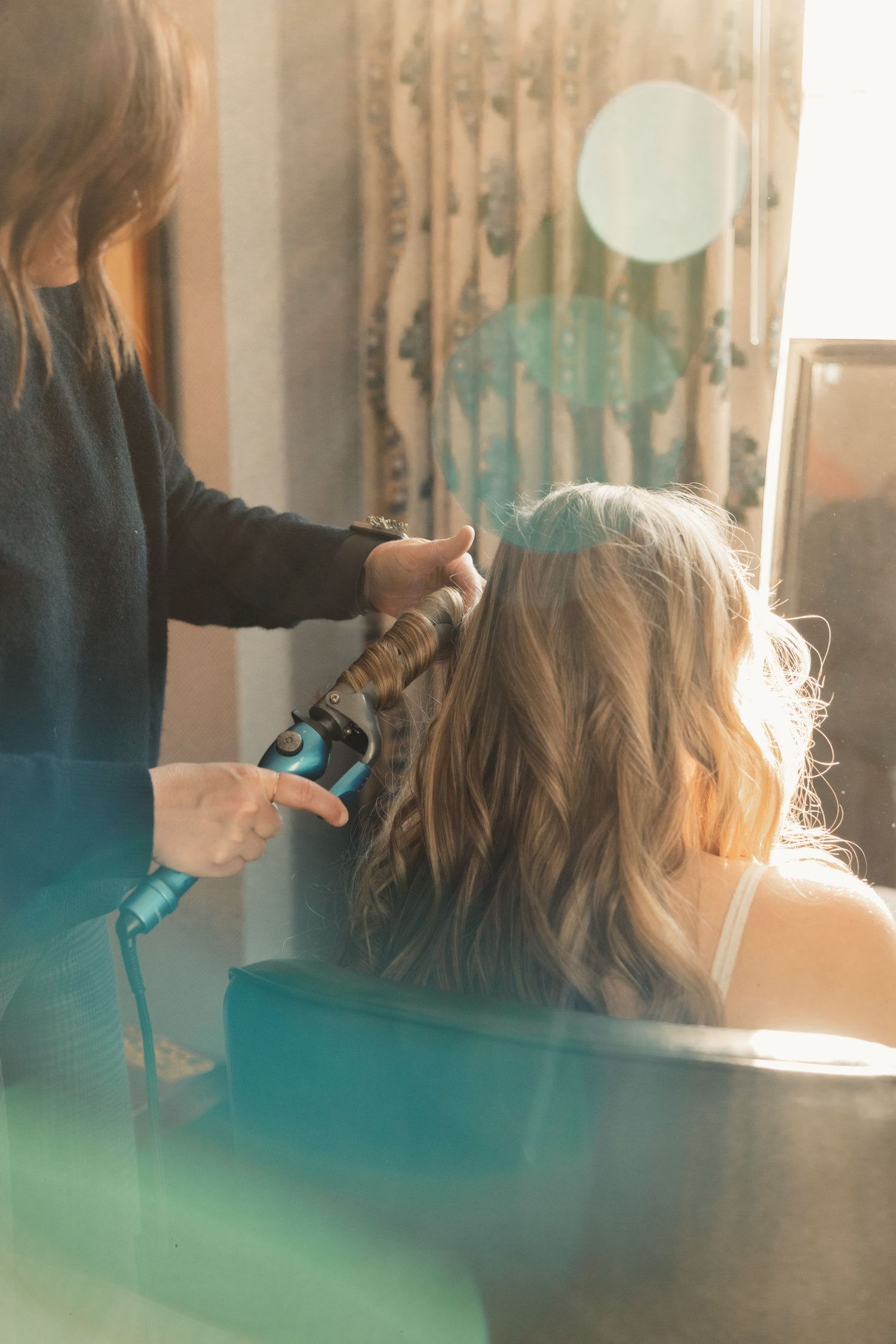 Hairstylist using curling iron on client's blonde hair.