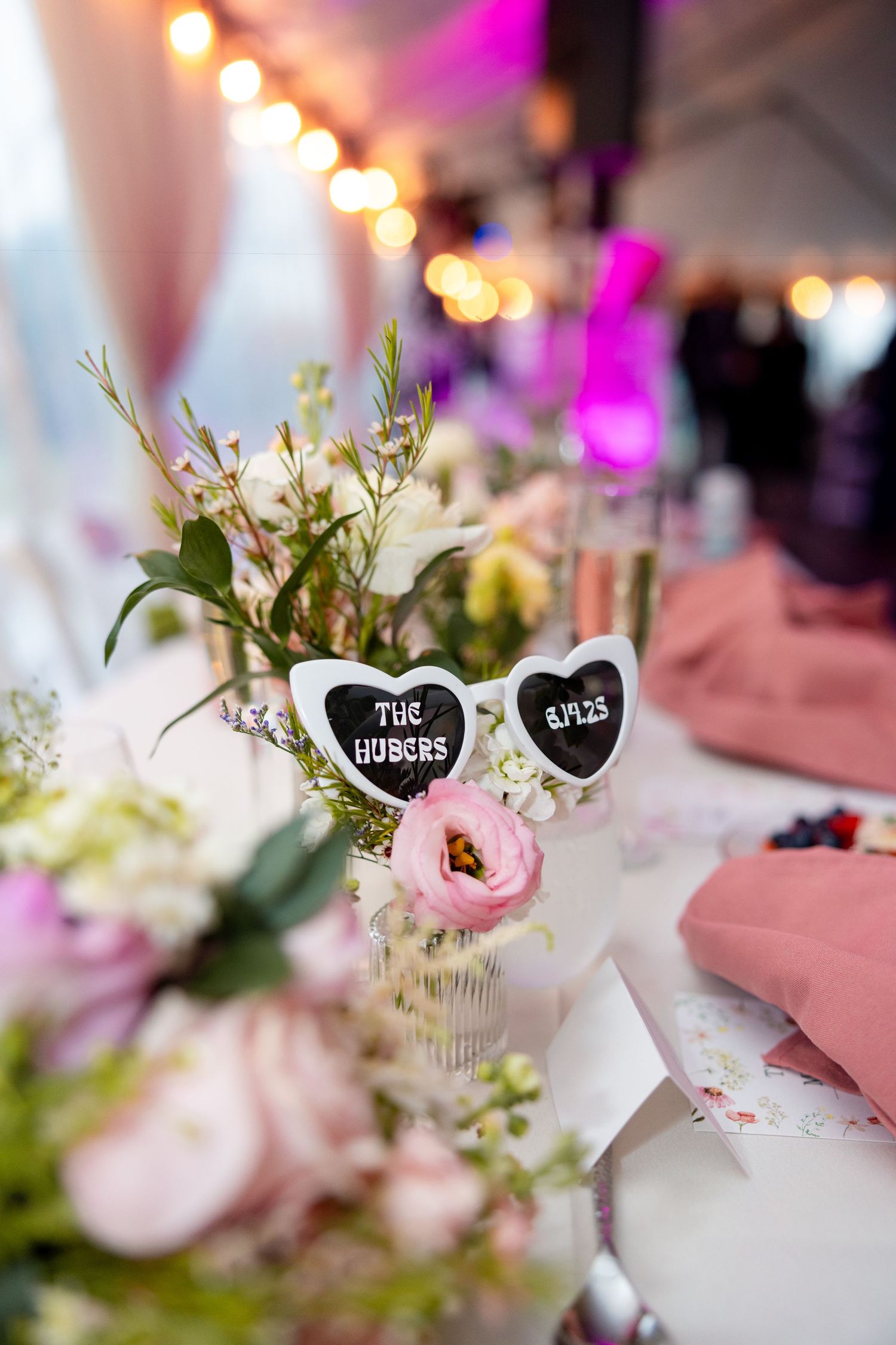 Wedding reception table decorations featuring heart-shaped name cards and delicate pink and white floral centerpieces.