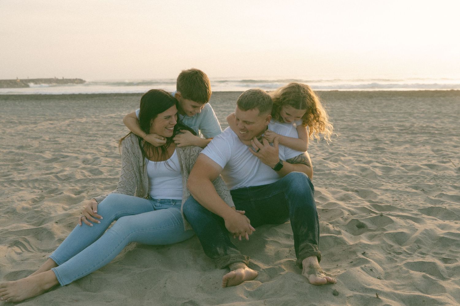 Family lying together on a sandy beach during sunset creating a romantic atmosphere.