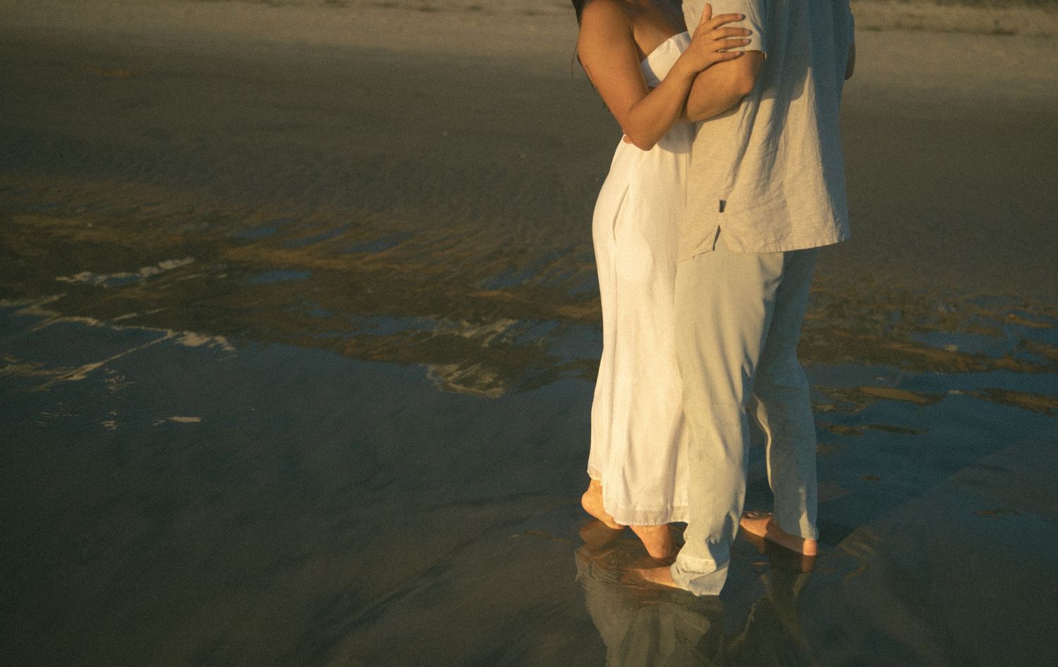 Couple walking along the ocean shore during sunset.