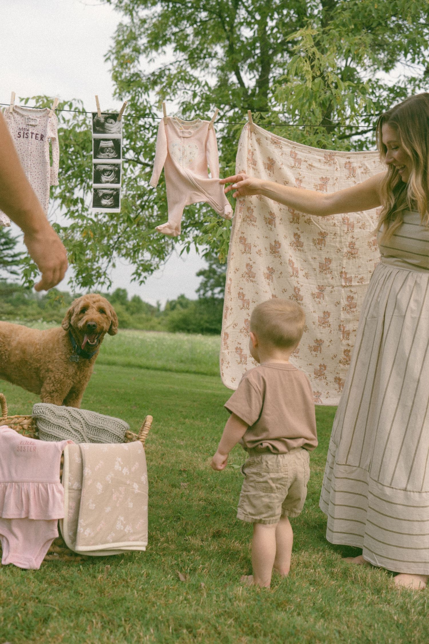 Pink and floral baby clothes hanging on a line with ultrasound photos displayed outdoors.