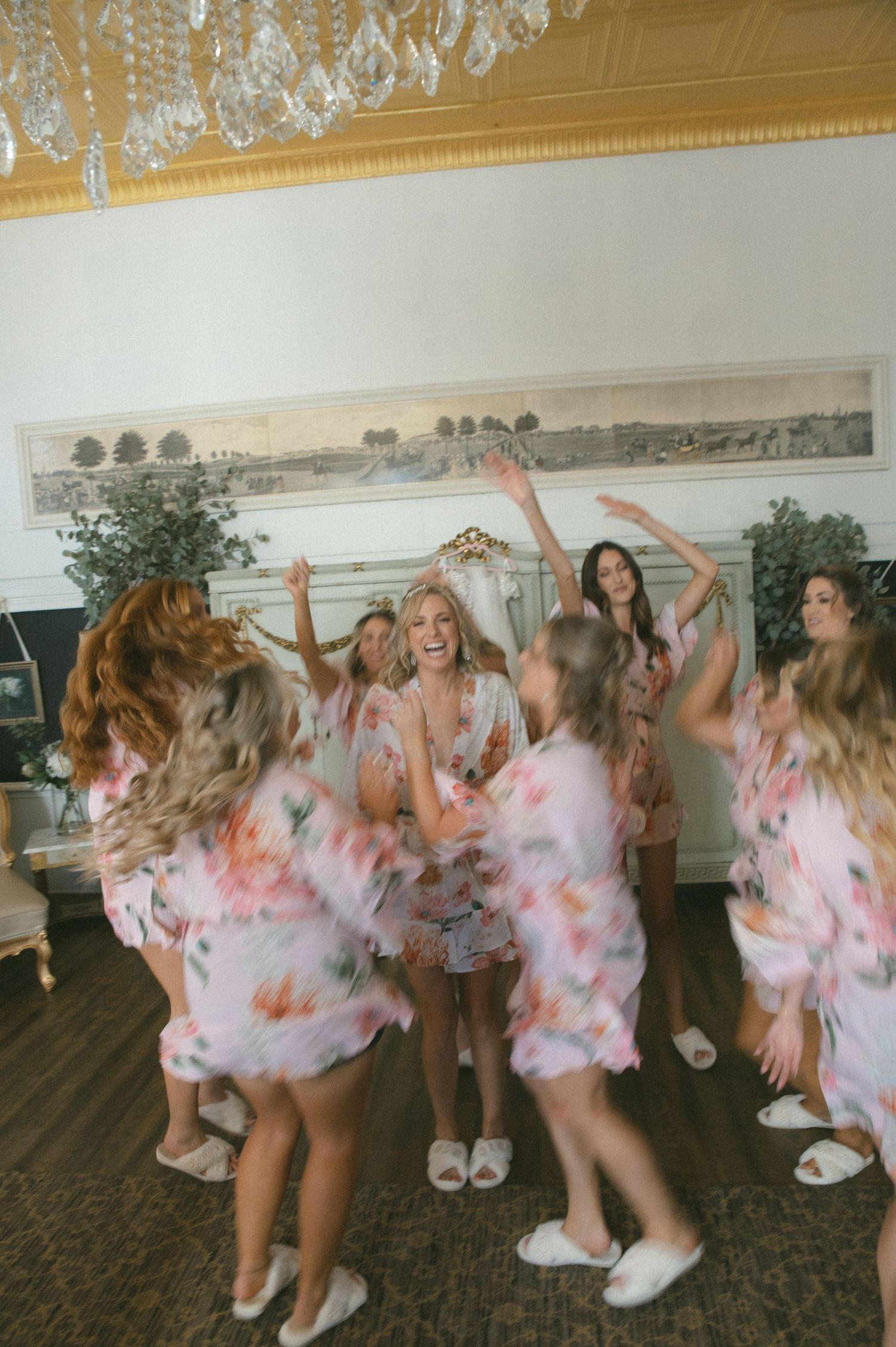 Bridesmaids in pink tie-dye dresses dance together at a wedding reception.