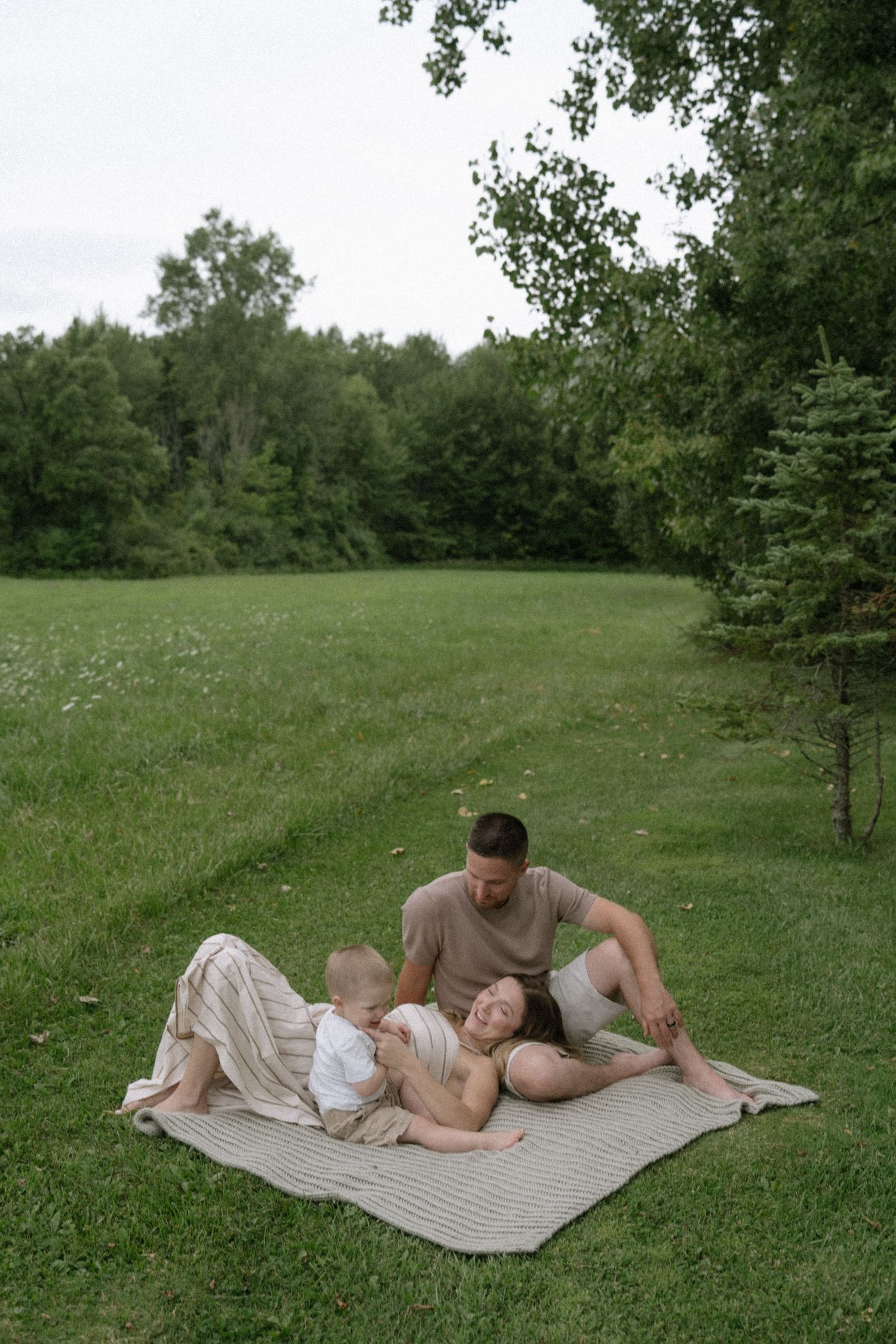 A family relaxing together on a blanket in a serene green field.