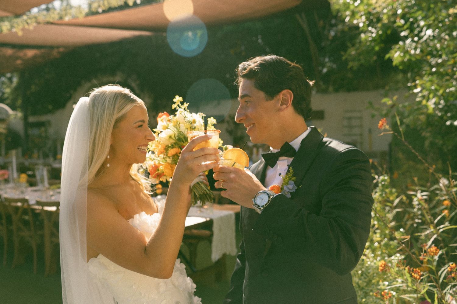 Sunlit outdoor wedding moment with champagne toast.