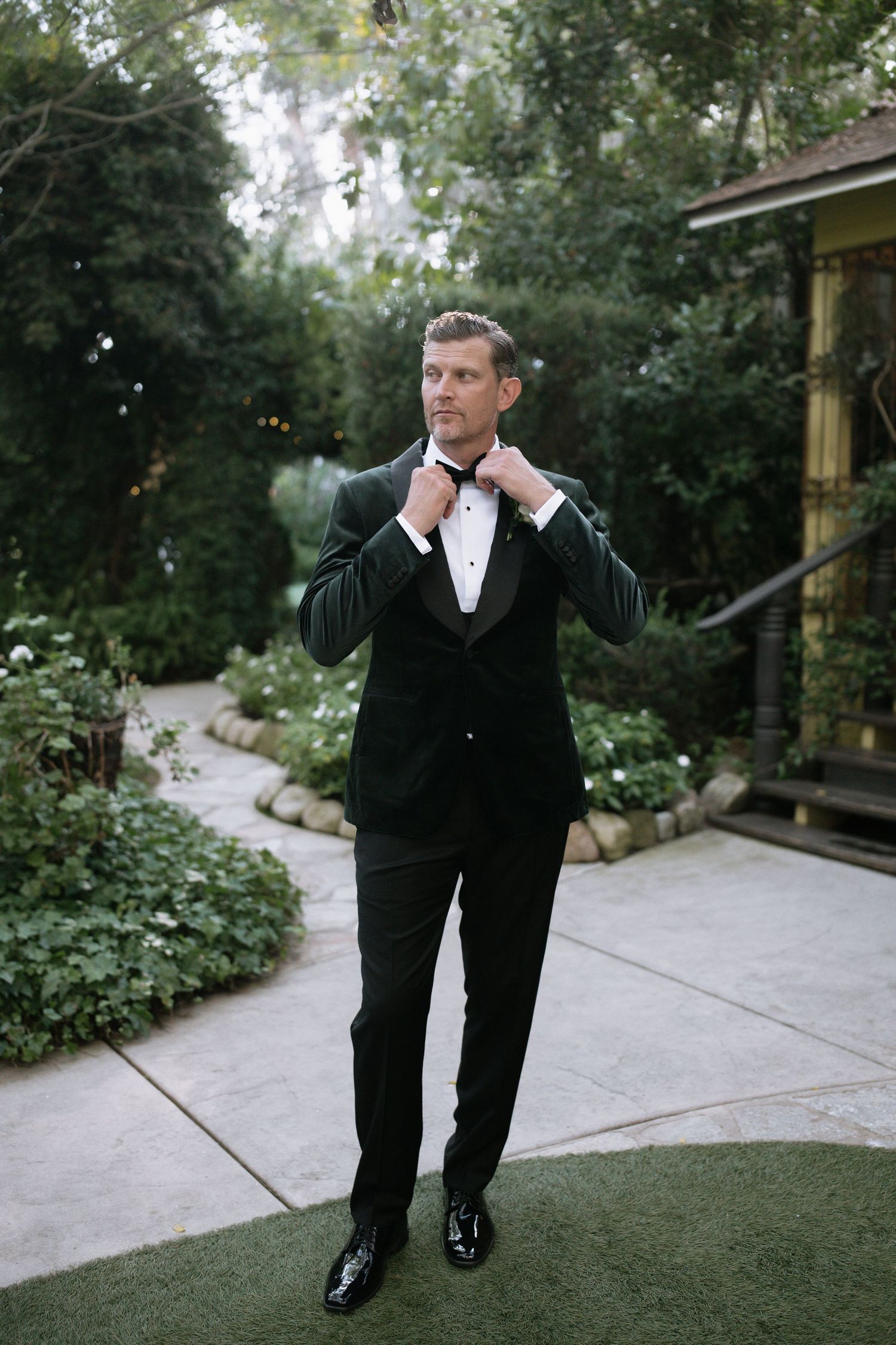 A couple walks along a garden path during their wedding photoshoot.