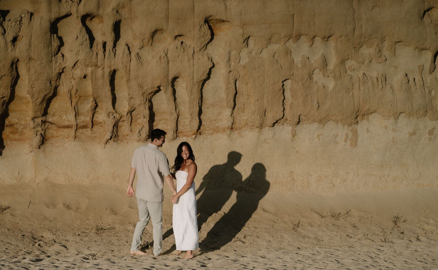 Shadows cast on a sandy beach cliff during golden hour.