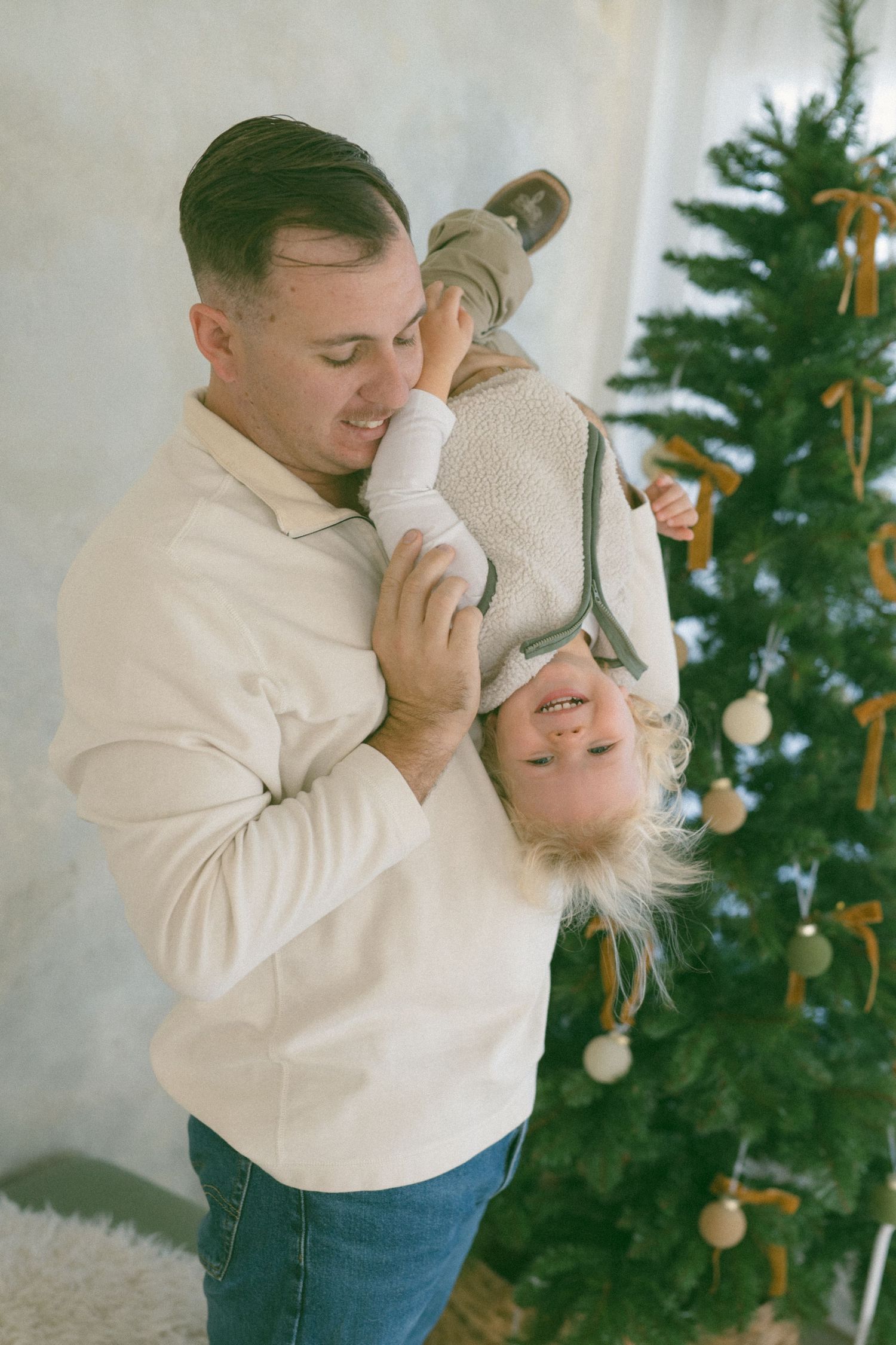 Playful Family sharing intimate moments in front of a decorated Christmas tree.
