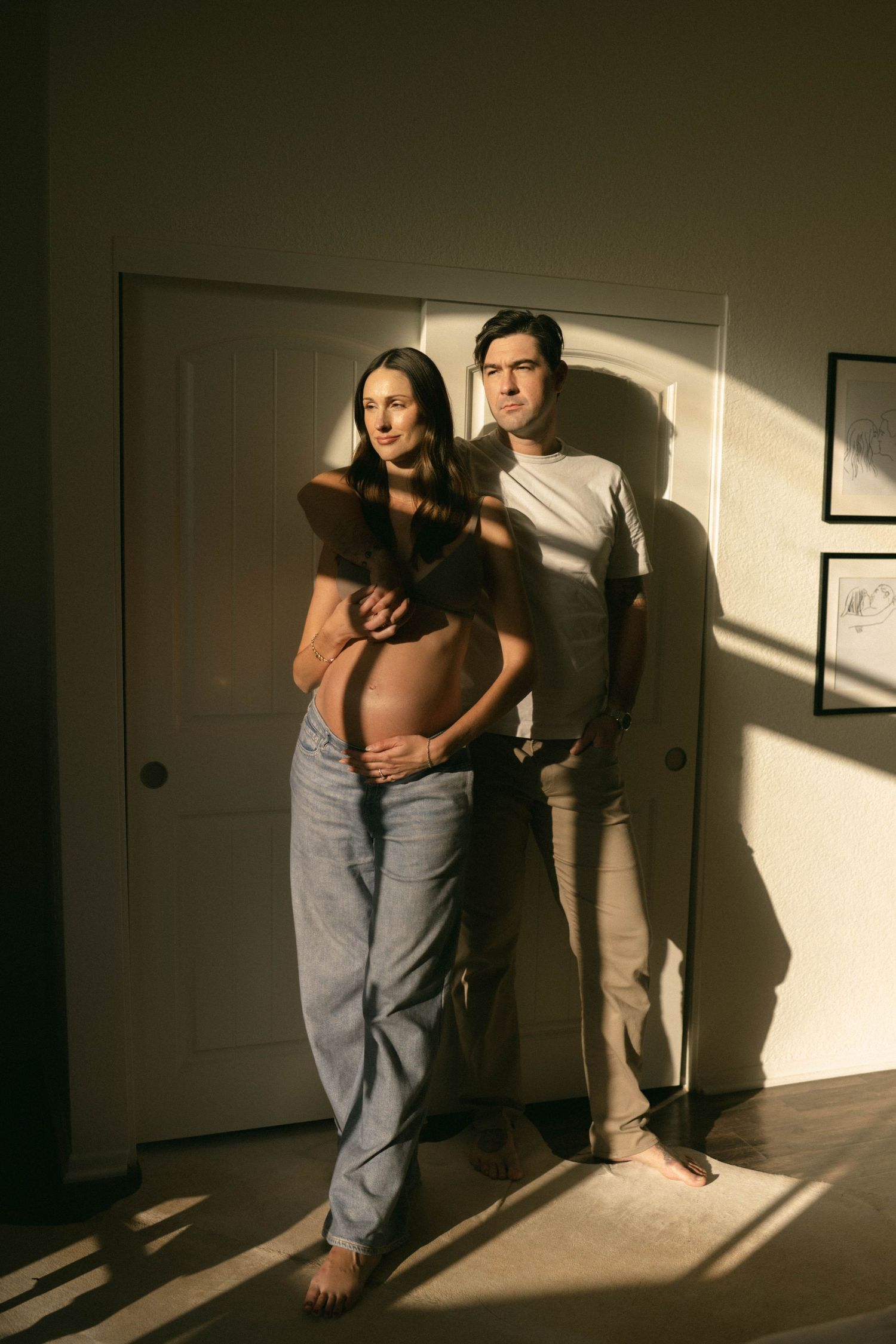 Artistic silhouette photo of couple embracing in sunlit room. Maternity.