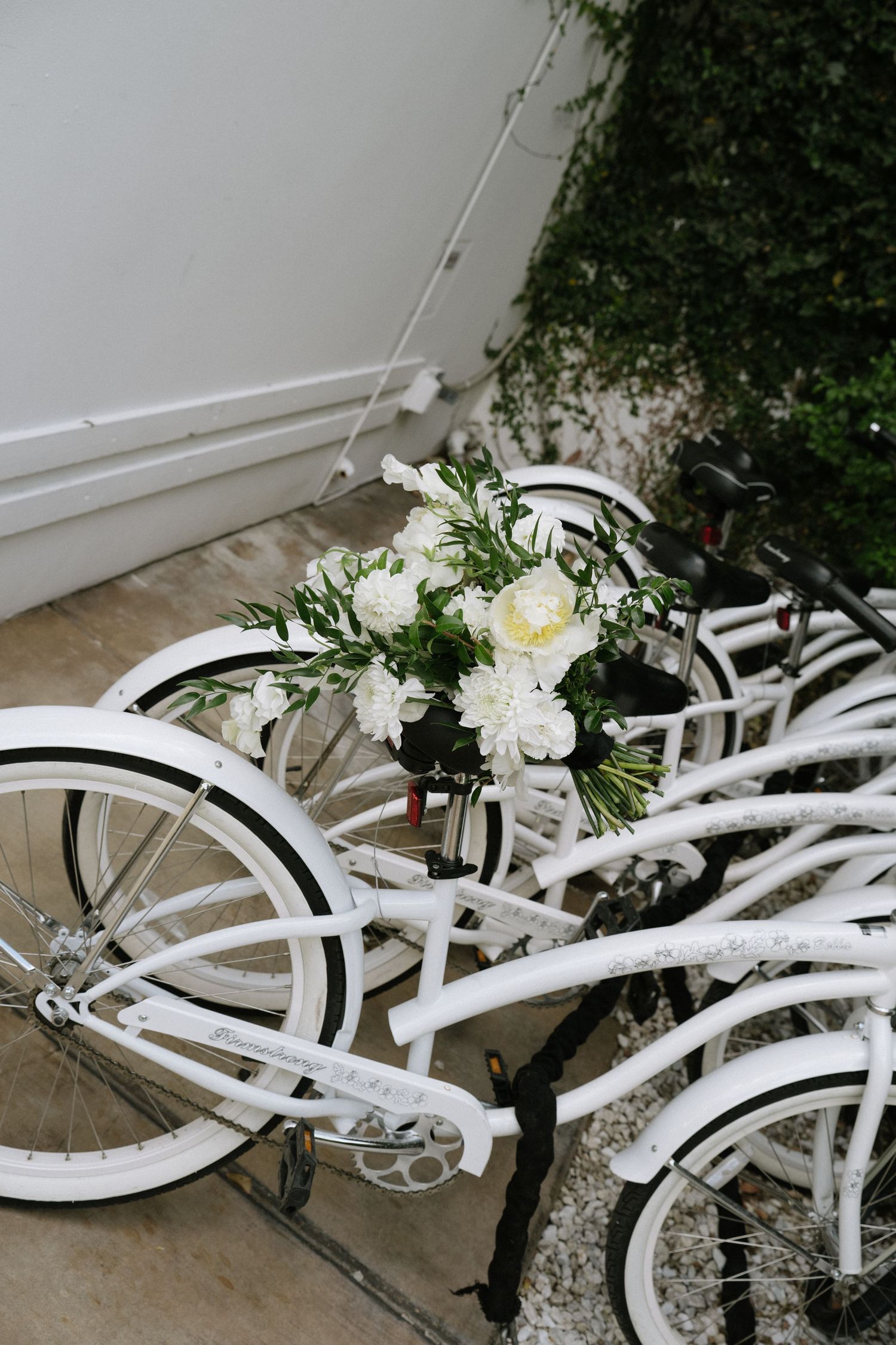 A white vintage bicycle decorated with white flowers and greenery for a wedding.