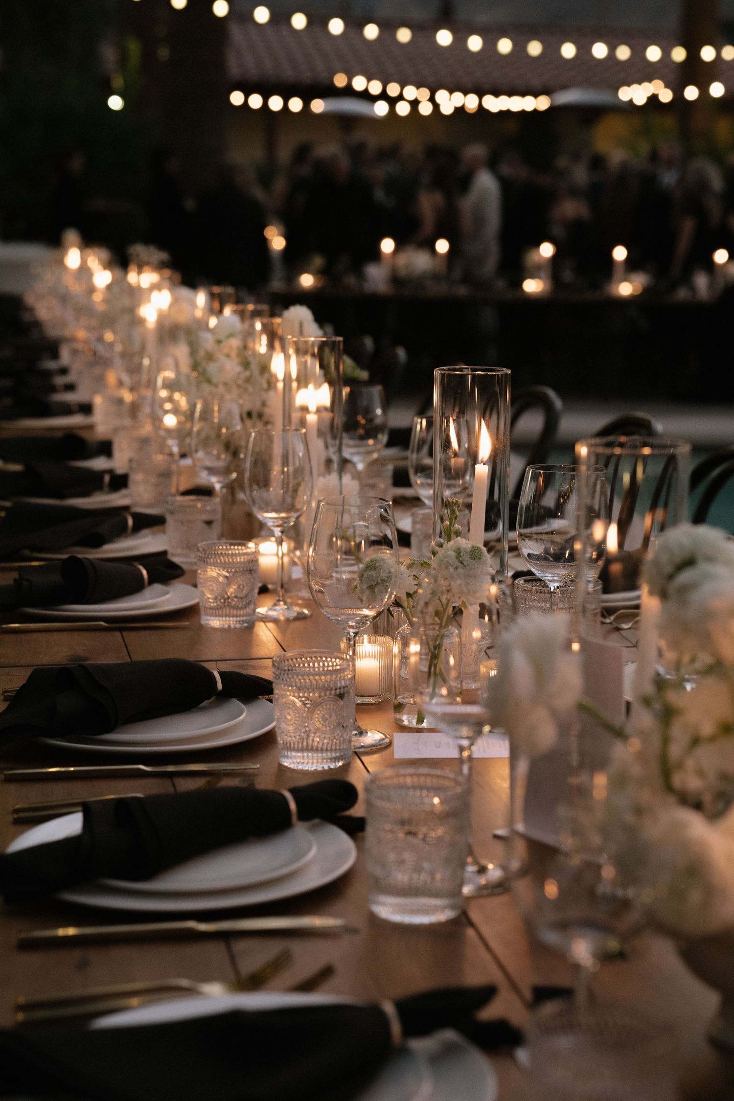 Elegant table settings with string lights and candlelight creating romantic ambiance.