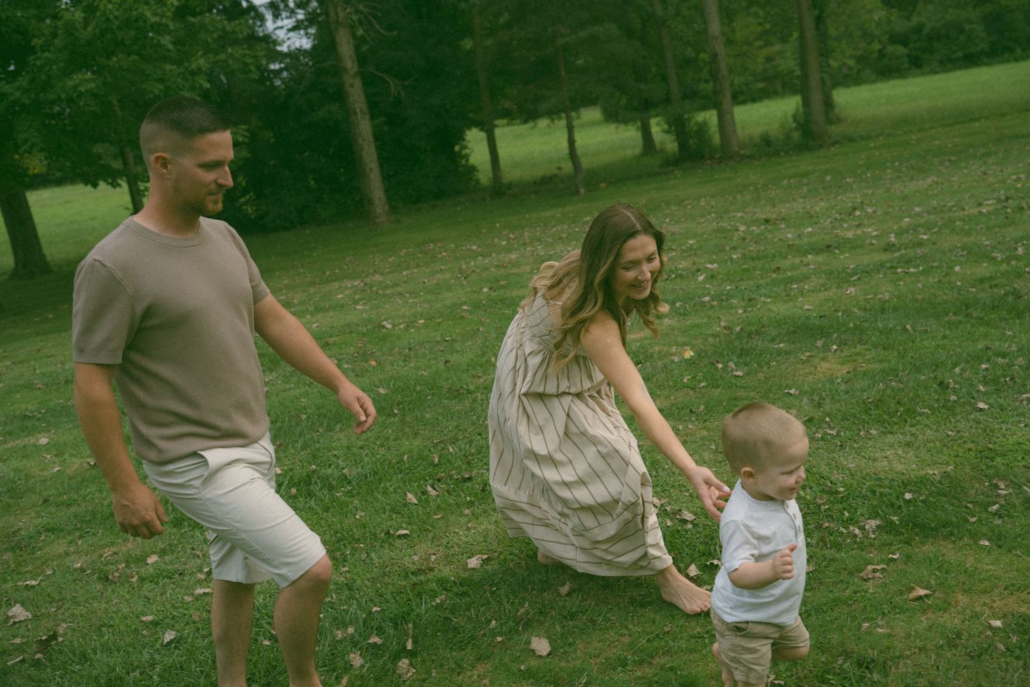 A family plays together in a sunny green field on a summer day.