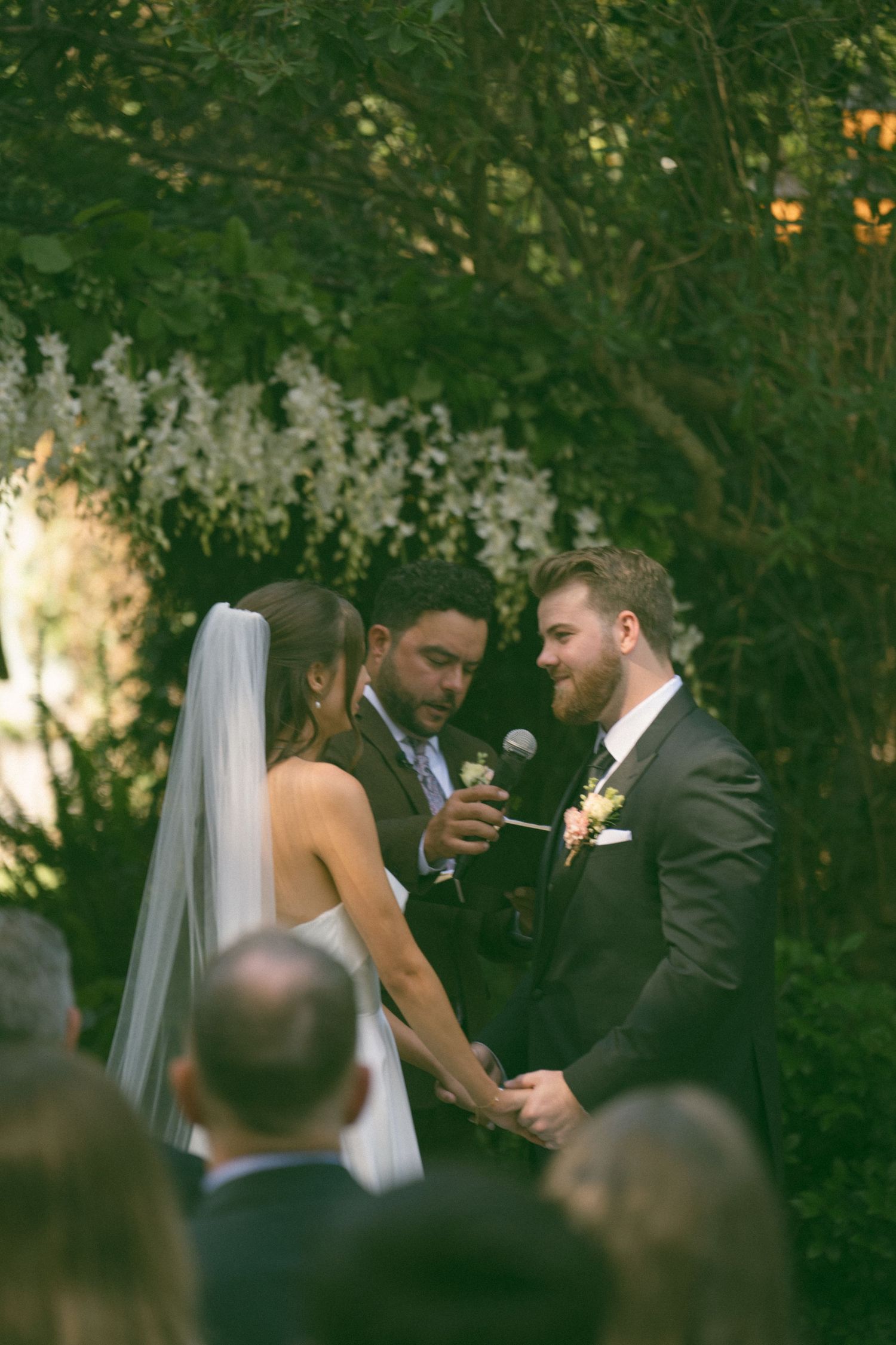 An intimate outdoor wedding ceremony with guests watching the couple exchange vows.