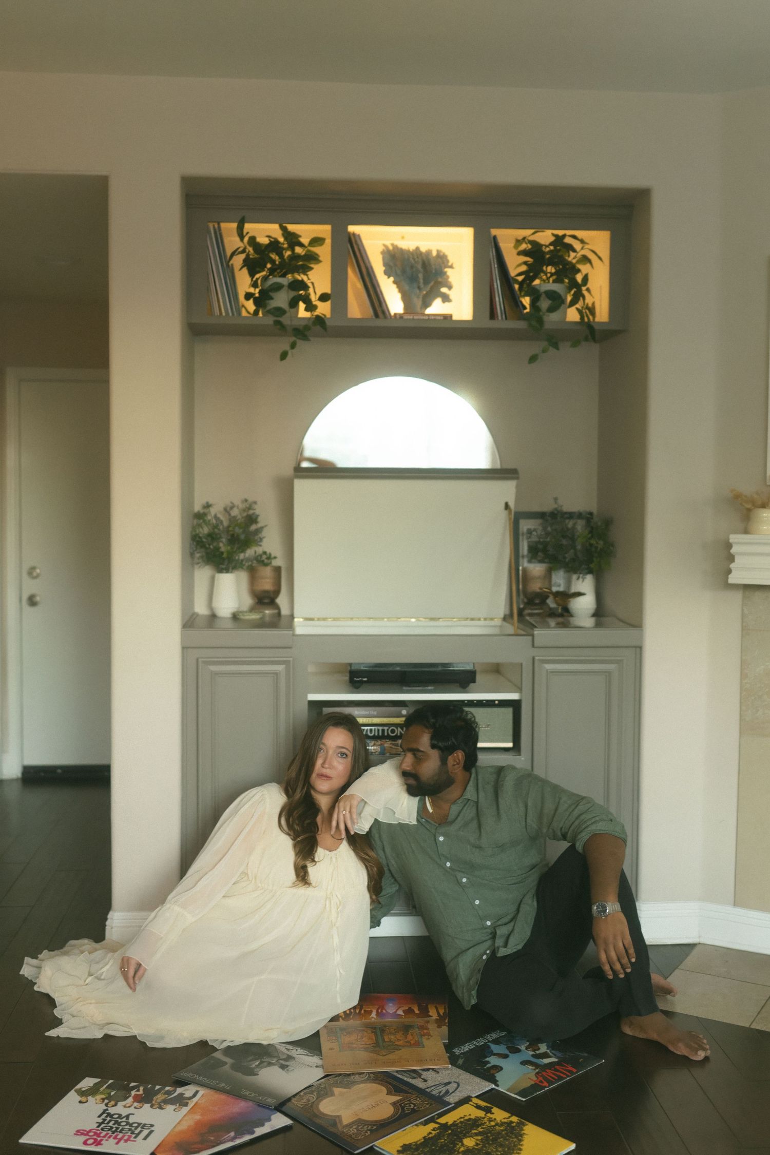 Two people relax on a couch in a bright living room with decorative windows.