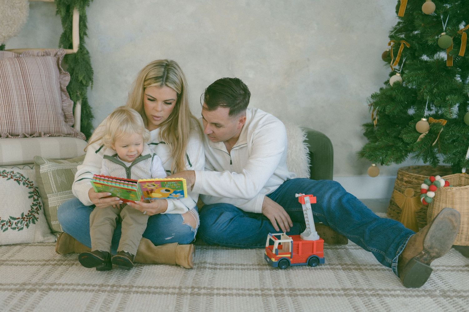 Couple relaxing together while reading a book near a Christmas tree.