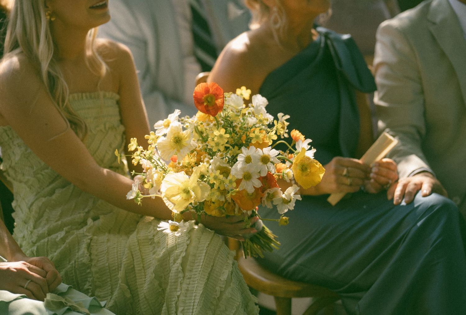 Sunlit detail shot of yellow and white floral bouquet at outdoor wedding.