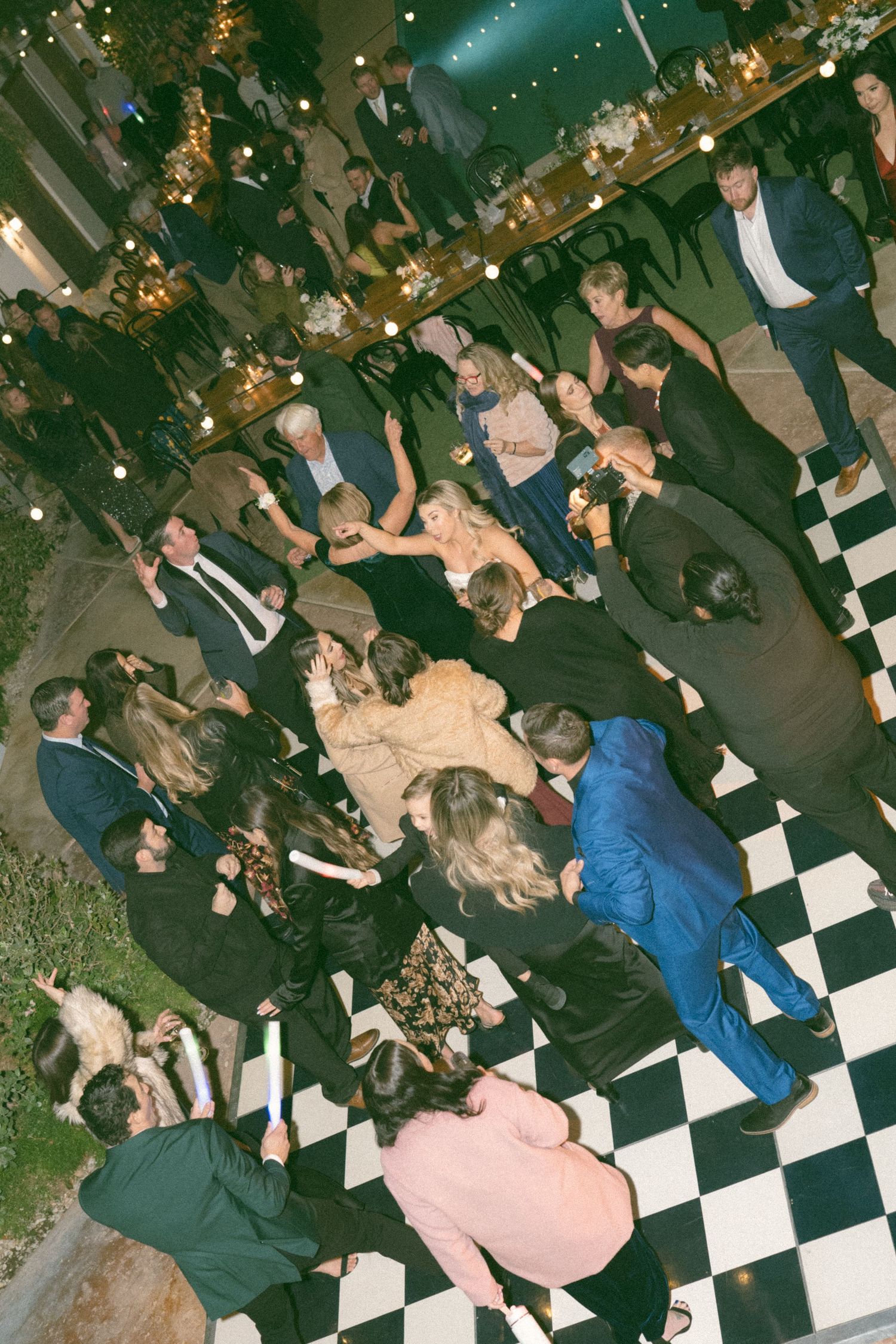 Overhead view of wedding guests dancing on a black and white checkered dance floor.