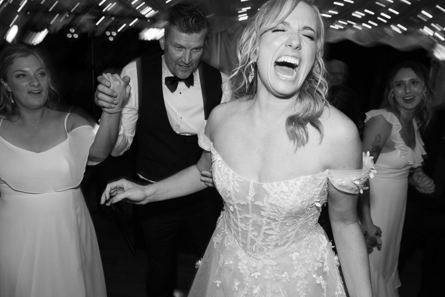 Wedding party members dancing and celebrating during the reception.