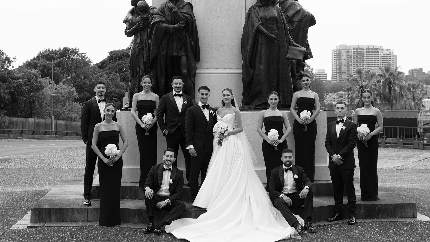 Black and white wedding party portrait with bride, groom, bridesmaids and groomsmen at monument.