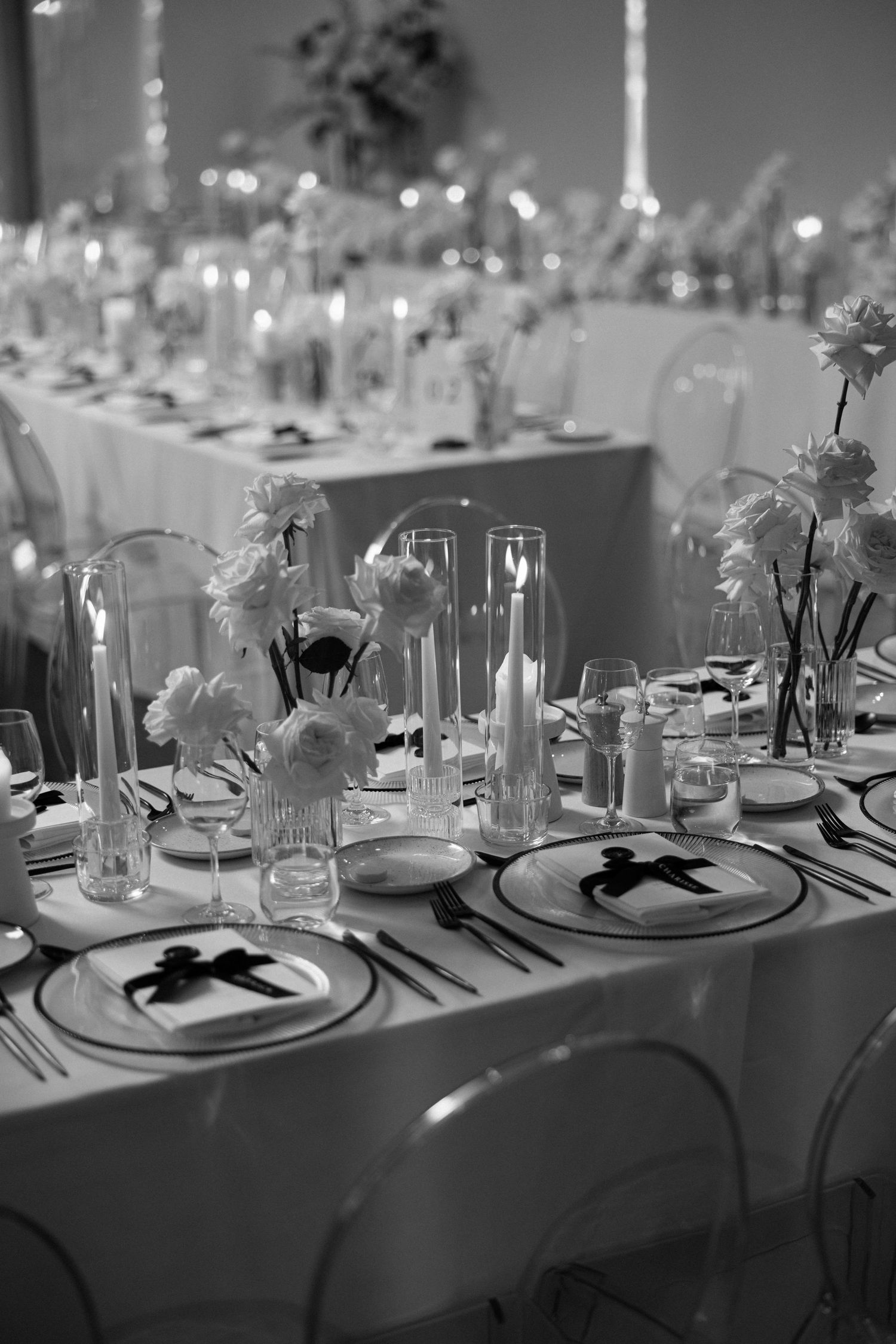 Elegant black and white wedding reception table with candles, flowers, and decorative plates.