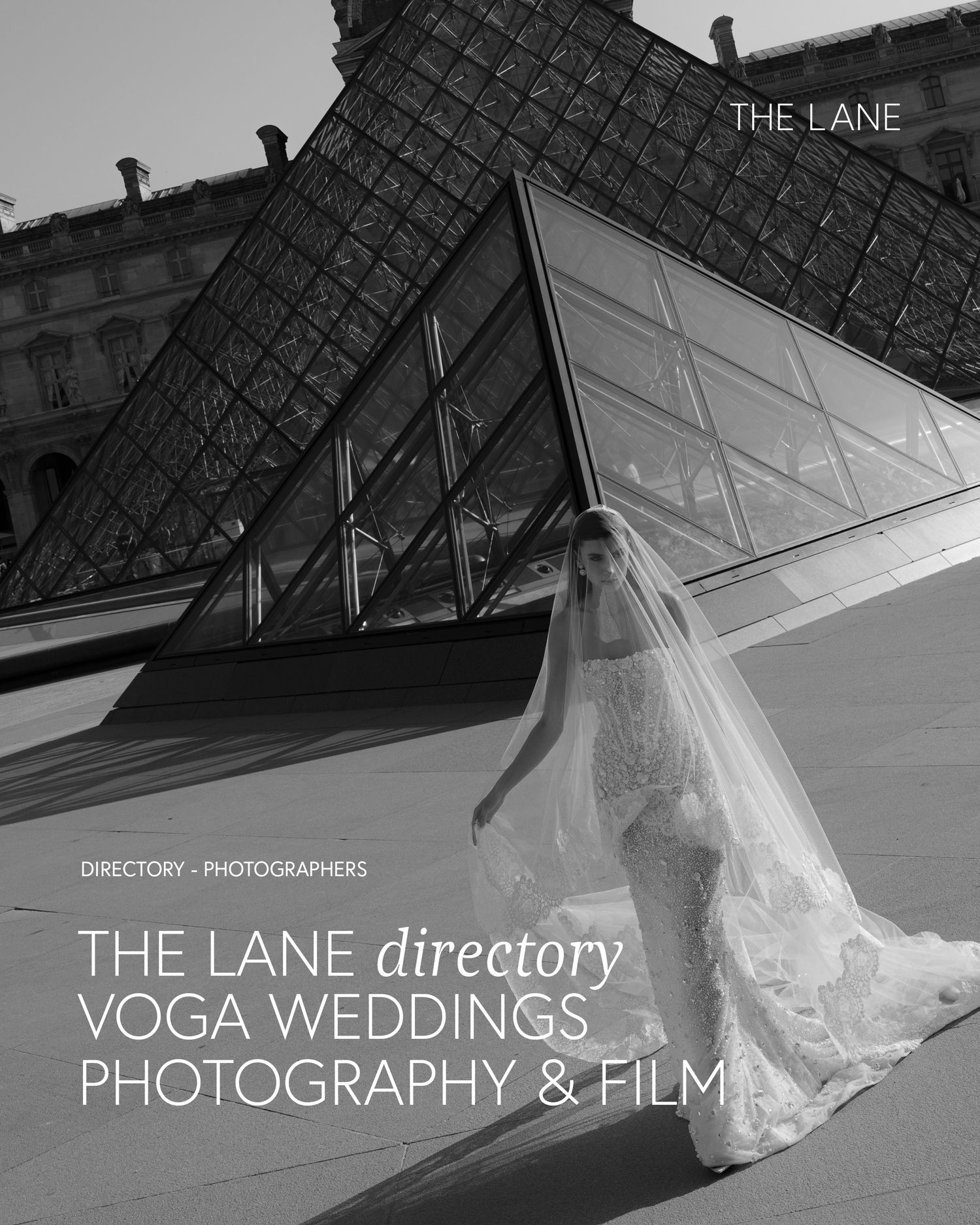 Bride in elegant gown with flowing veil poses before the Louvre pyramid in a stunning black and white wedding photo.