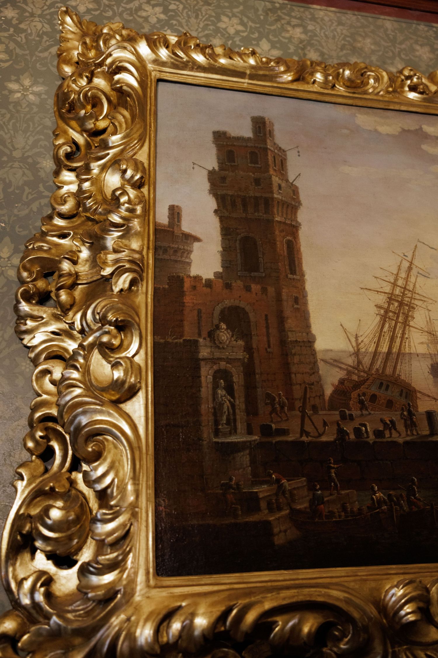 Ornate gilded gold frame surrounding classical oil painting of harbor scene with tower and sailing ships.