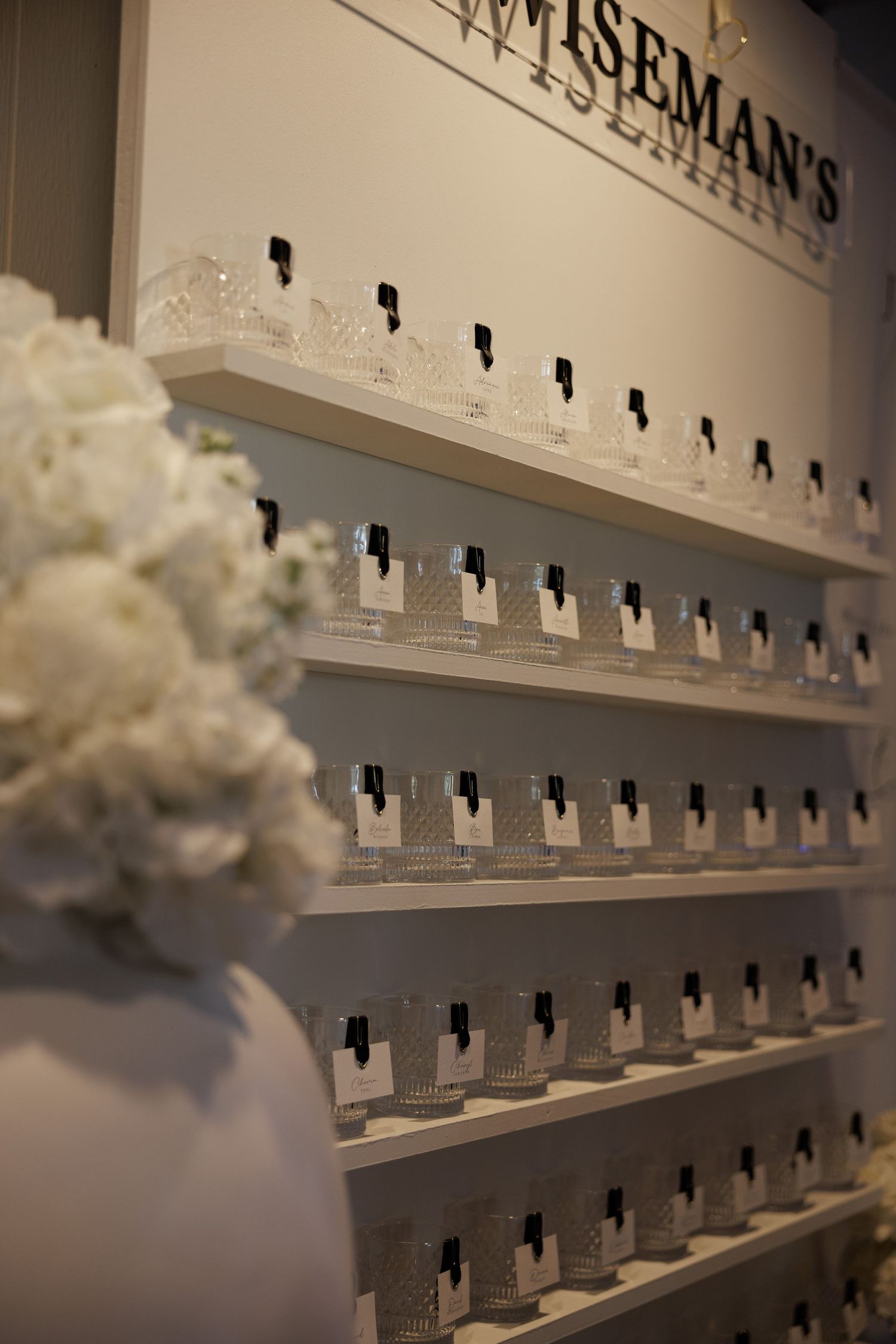 Wedding seating chart display wall with white flowers.