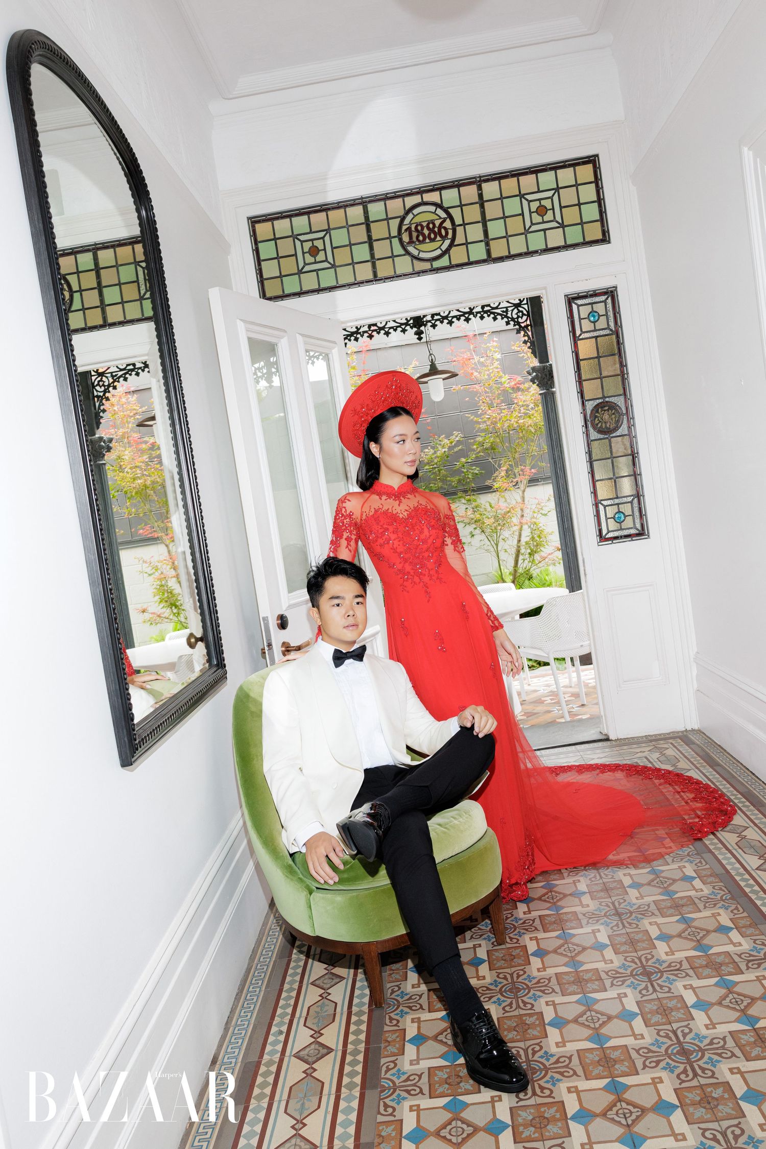 Couple in traditional Vietnamese wedding attire poses in elegant heritage home entryway.