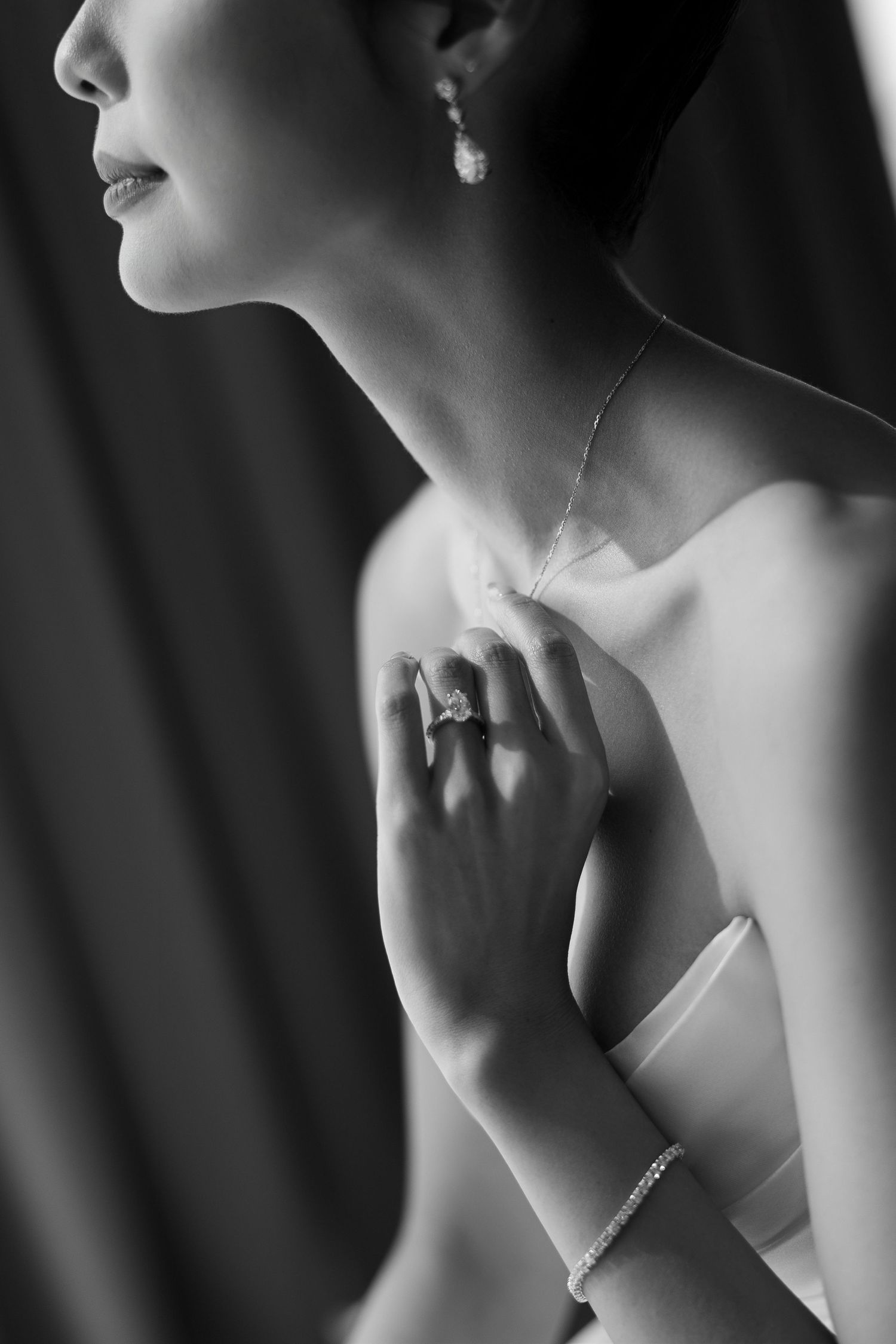 Close-up black and white bridal portrait showcasing diamond ring, bracelet, and pearl earrings.