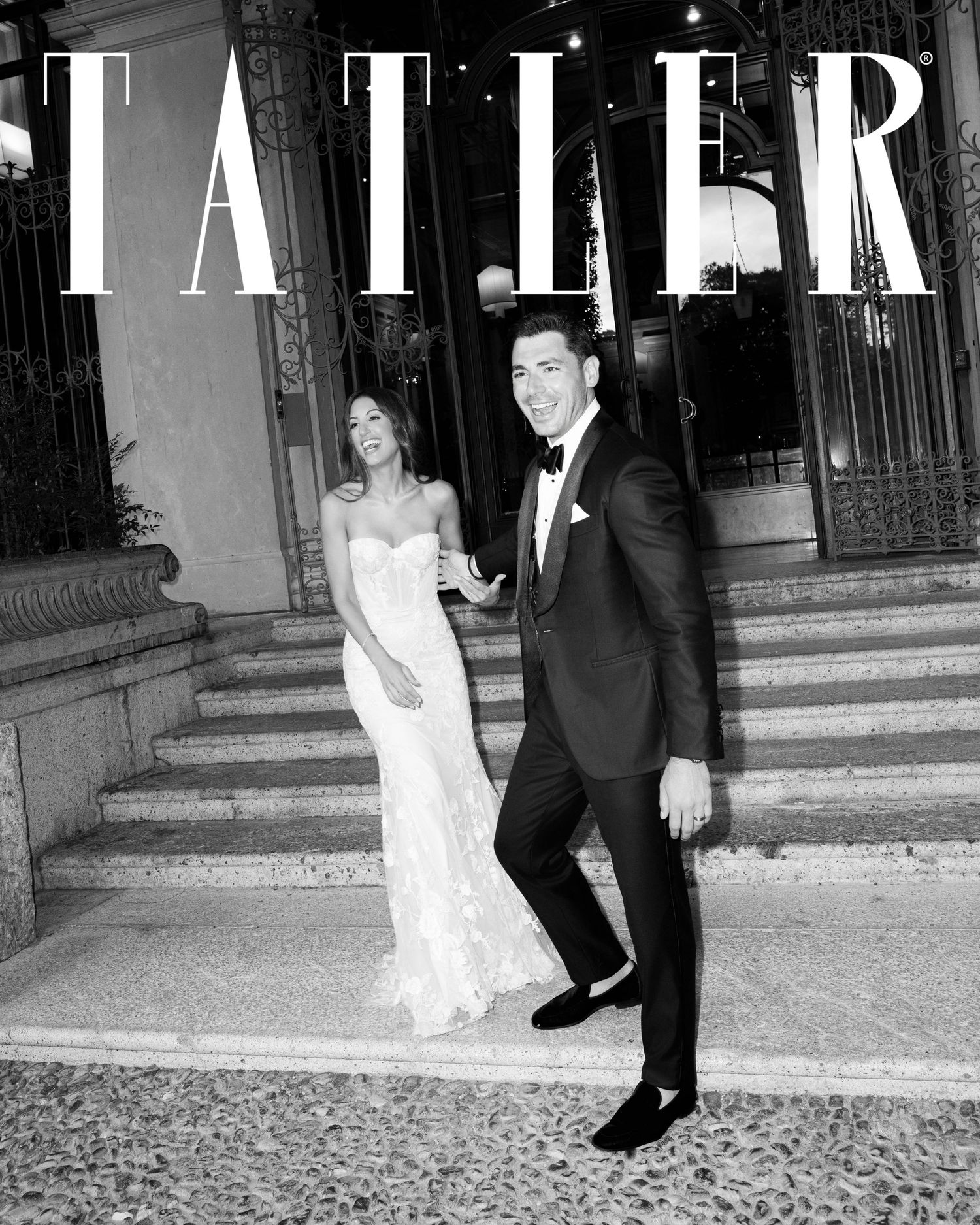 Elegant couple on Tatler magazine cover, bride in lace gown and groom in tuxedo on grand steps.