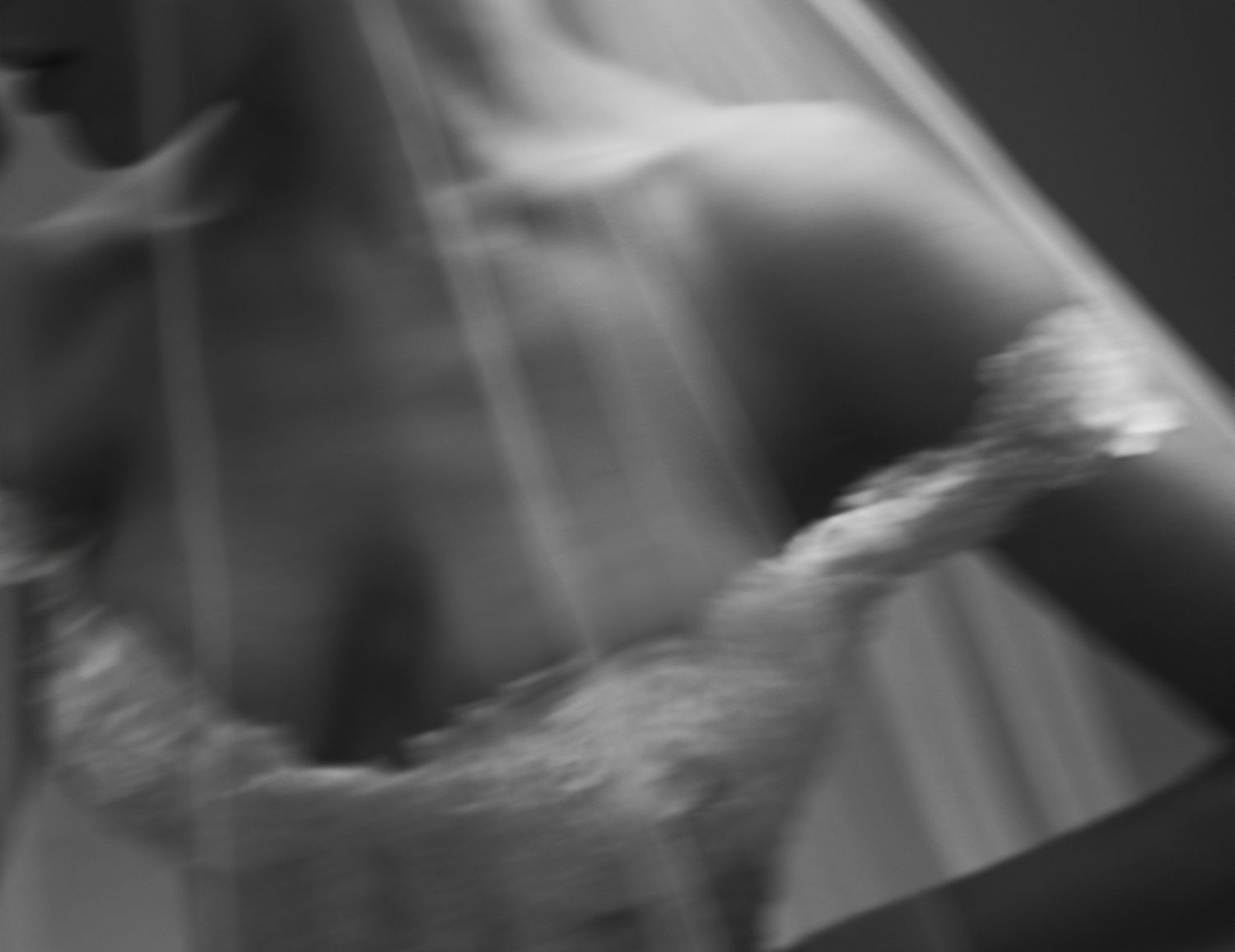 Blurred black and white photo of a bride in a wedding dress and veil, with soft light rays.
