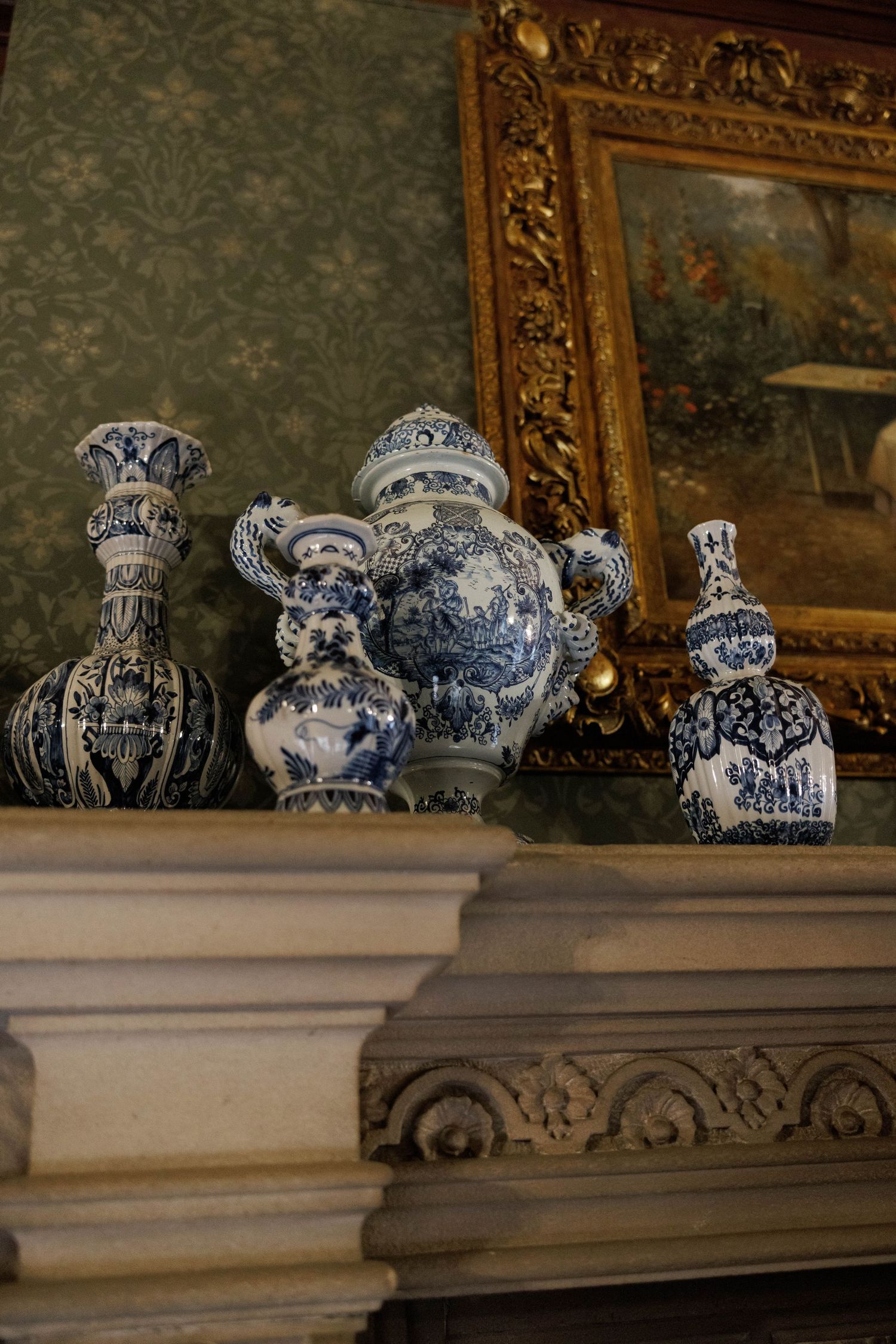 Antique blue and white Delft ceramic vases displayed on ornate fireplace mantel.